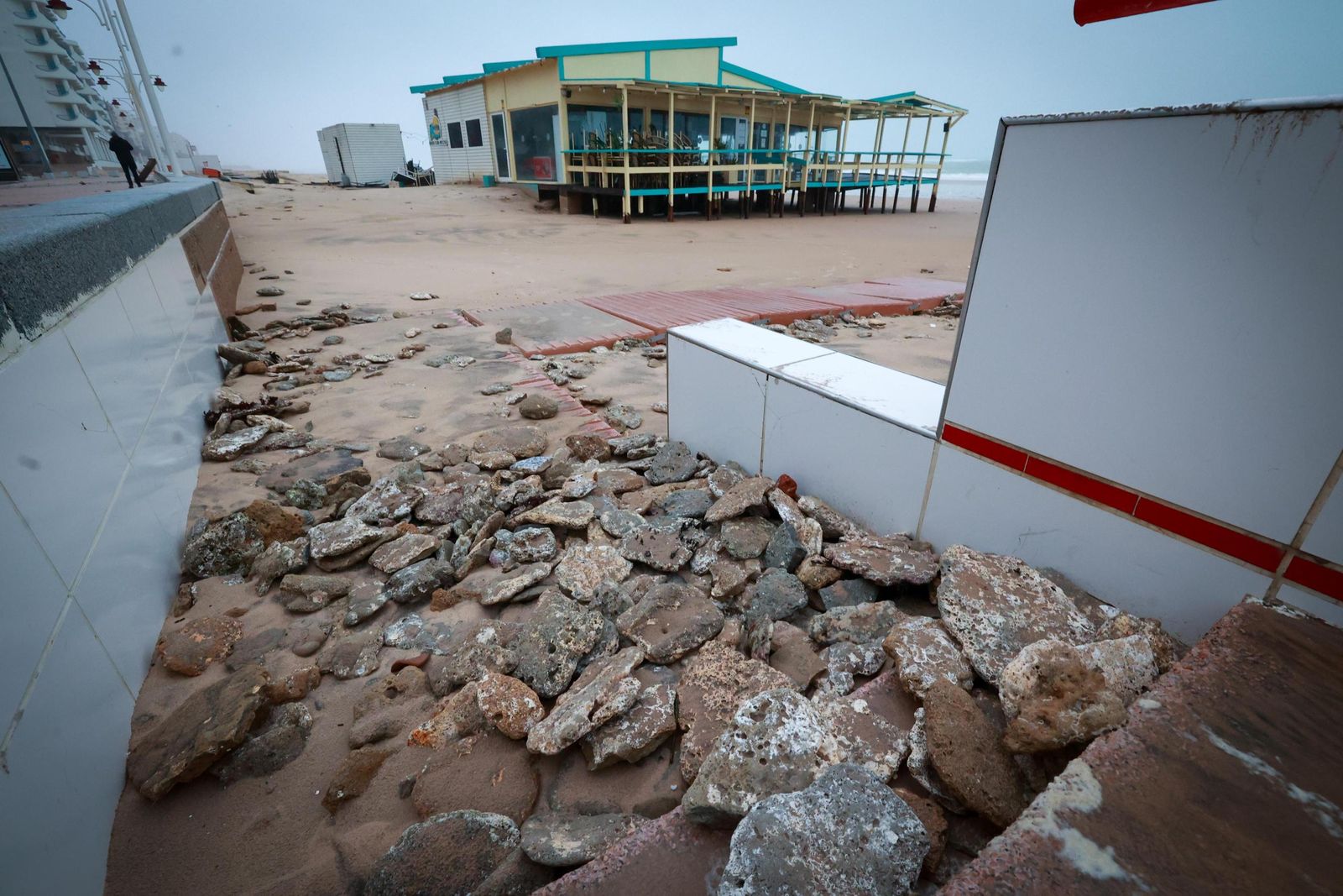 Piedras en uno de los accesos del Paseo Marítimo con el chiringuito Potito al fondo.
