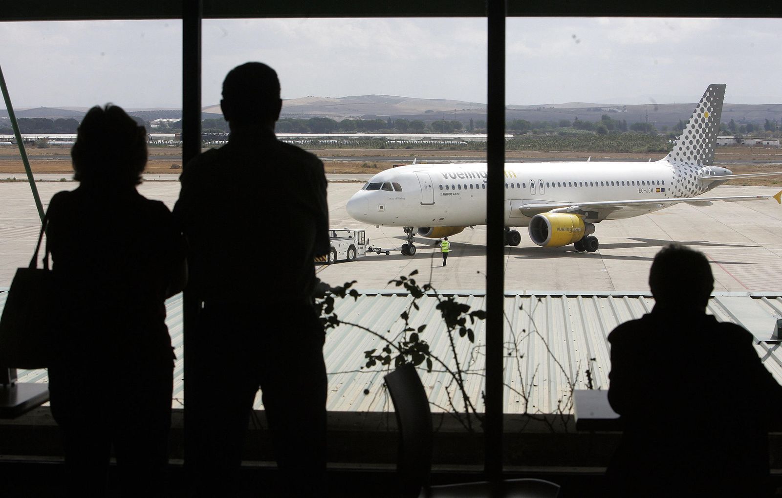 Varias personas observan el movimiento de aviones en el aeropuerto de Jerez.
