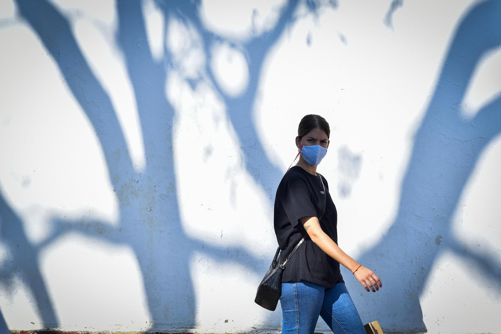 Una mujer camina portando una mascarilla.