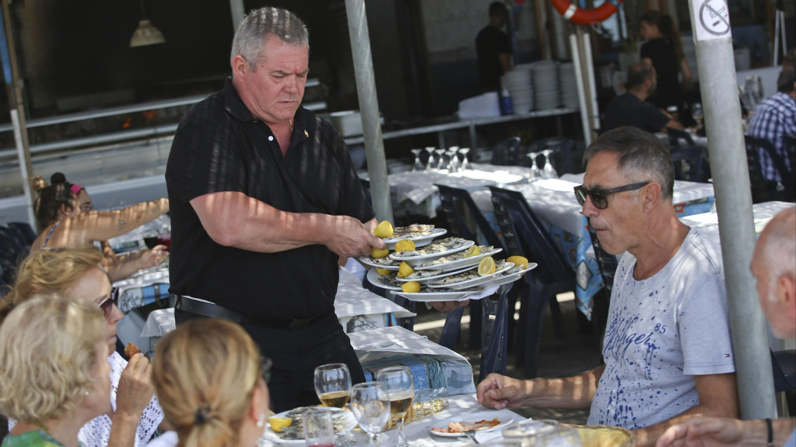 Un camarero sirve a unos clientes en un chiringuito.