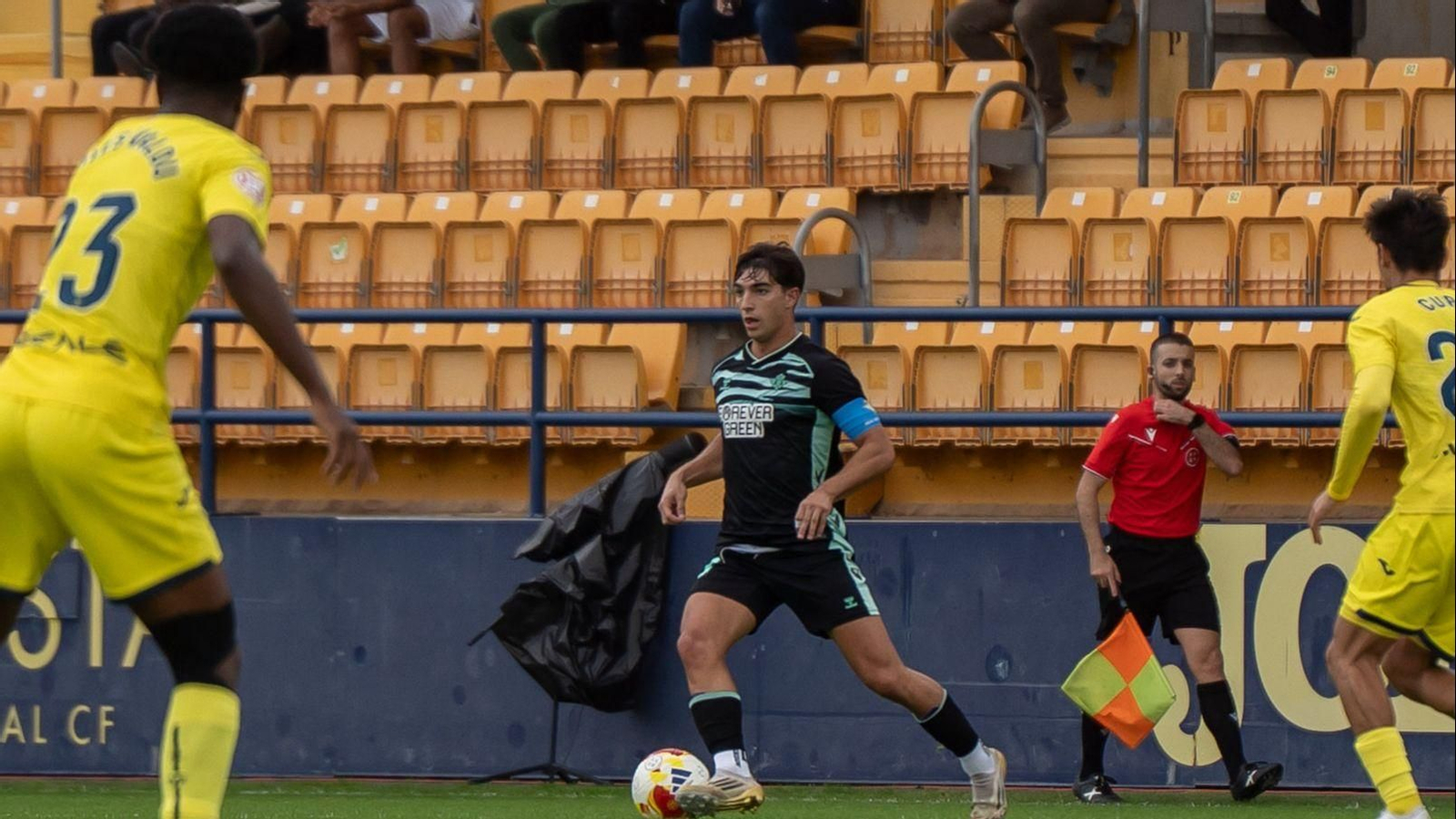 Carlos Reina se perfila para dar un pase ante la mirada de dos jugadores rivales.