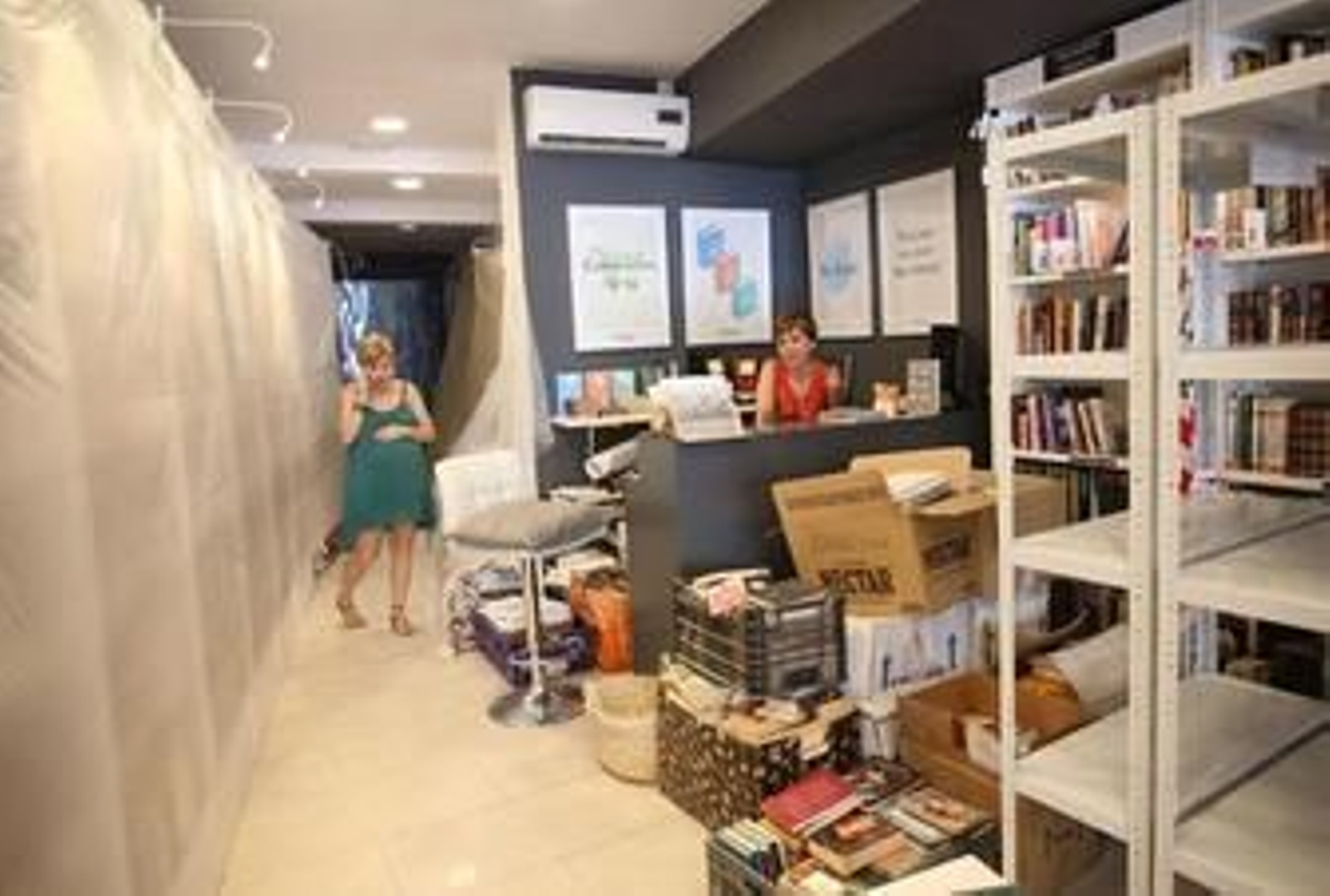 María, junto a las estanterías cubiertas con un plástico y Carmen, en el mostrador y rodeadas de cajas.