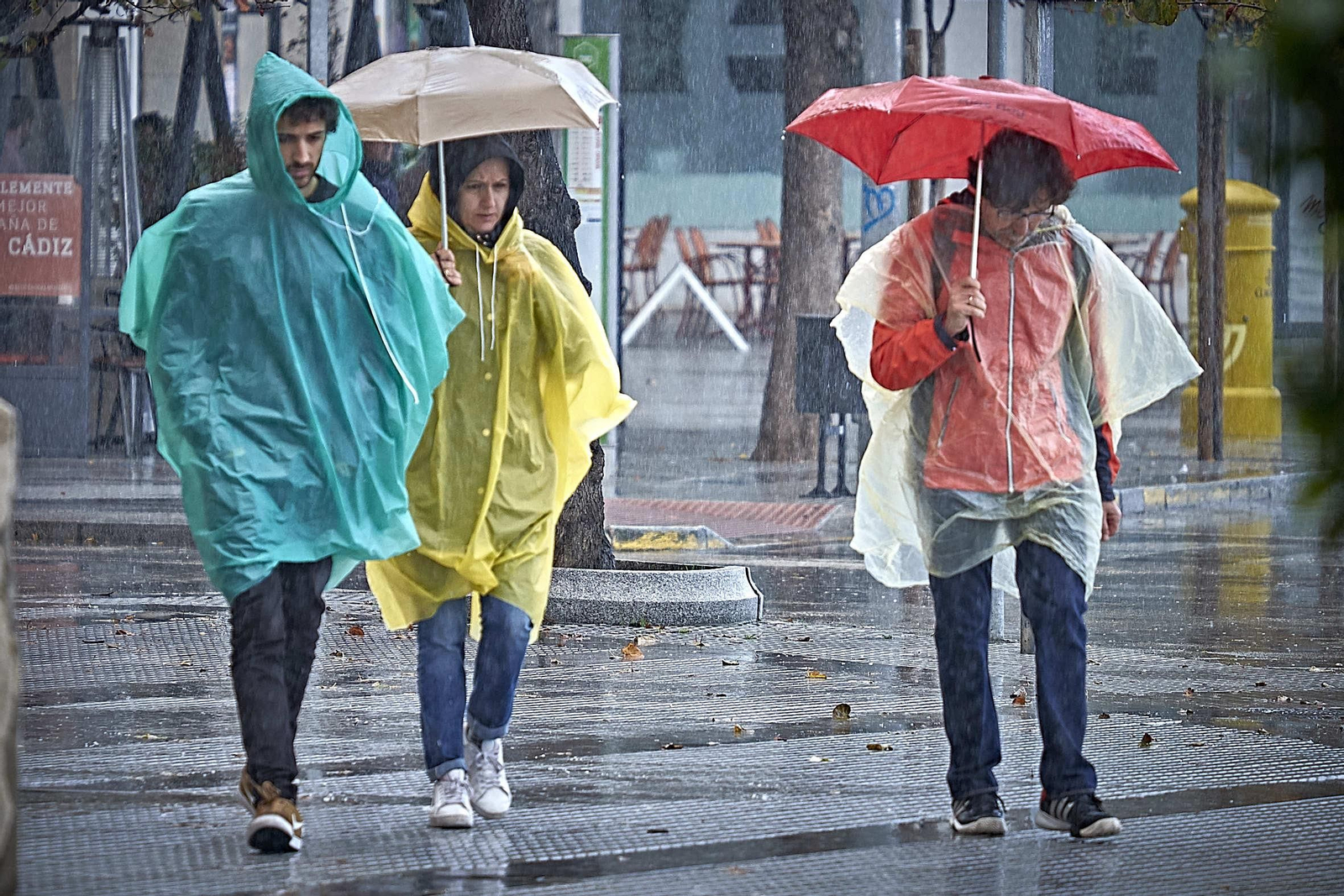 Tres personas se protegen de la lluvia.