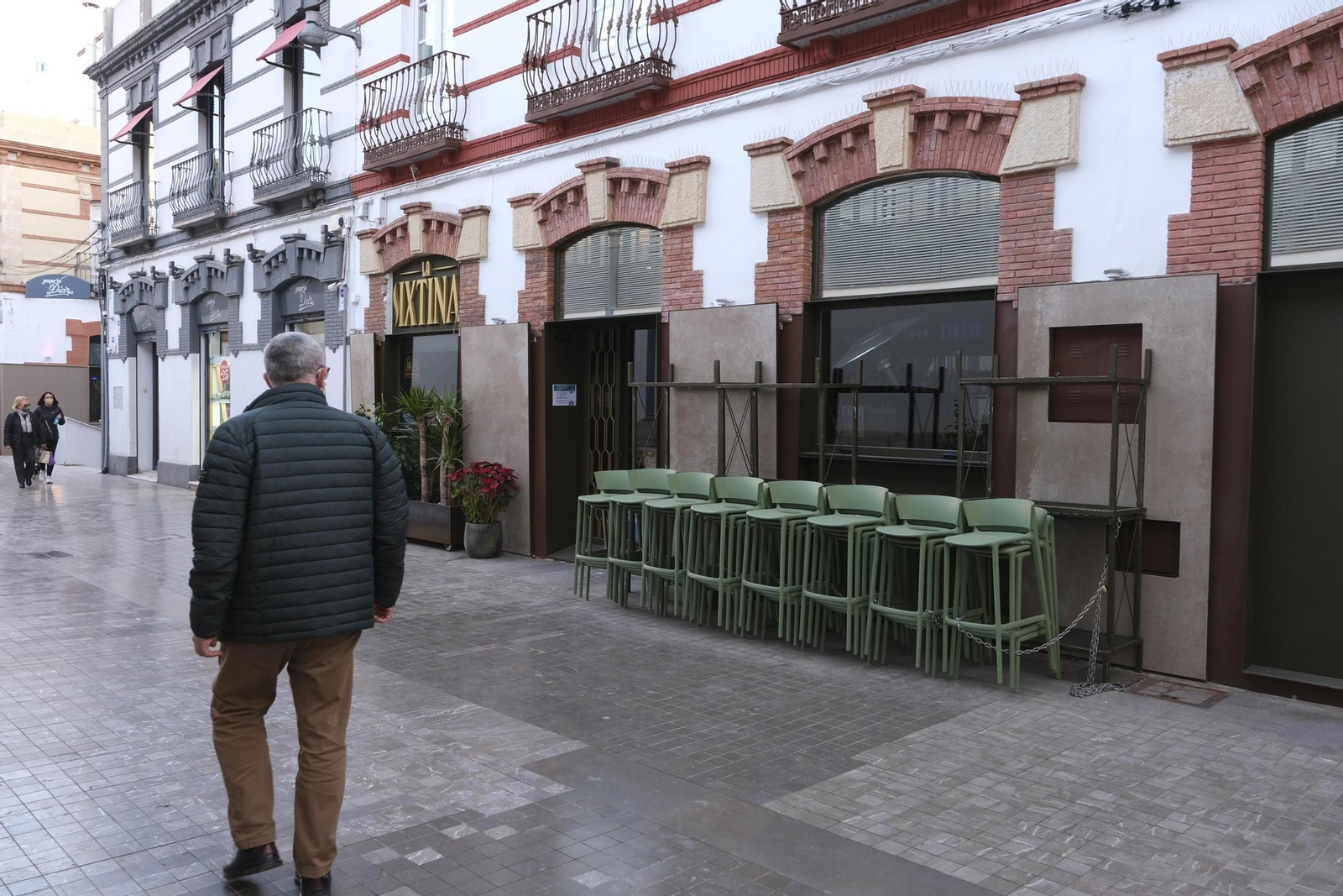 Un hombre observa las sillas recogidas de La Sixtina, junto al Mercado Central.
