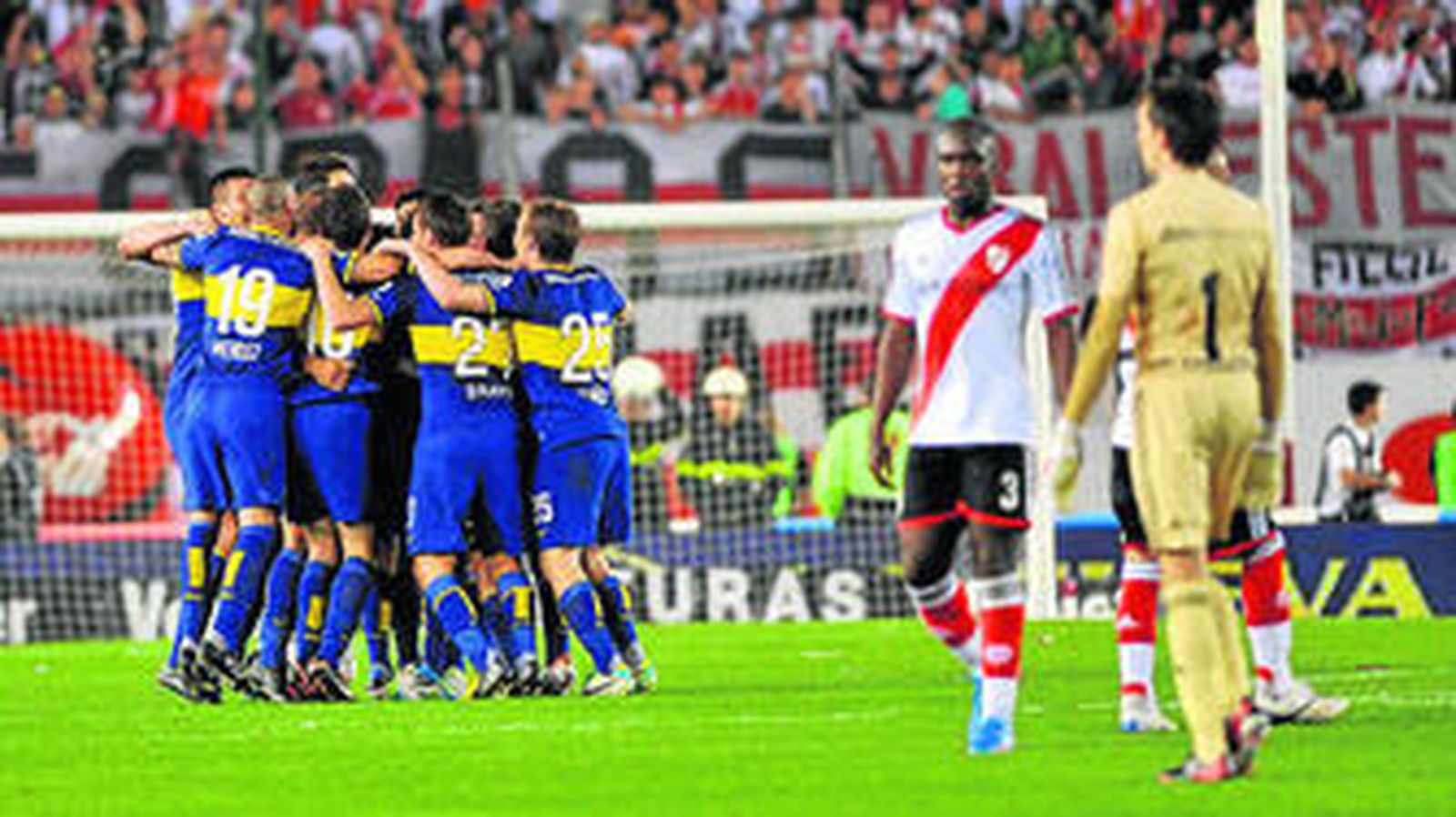 Los futbolistas de Boca Juniors festejan en el centro del campo ante el pesar de los de River.