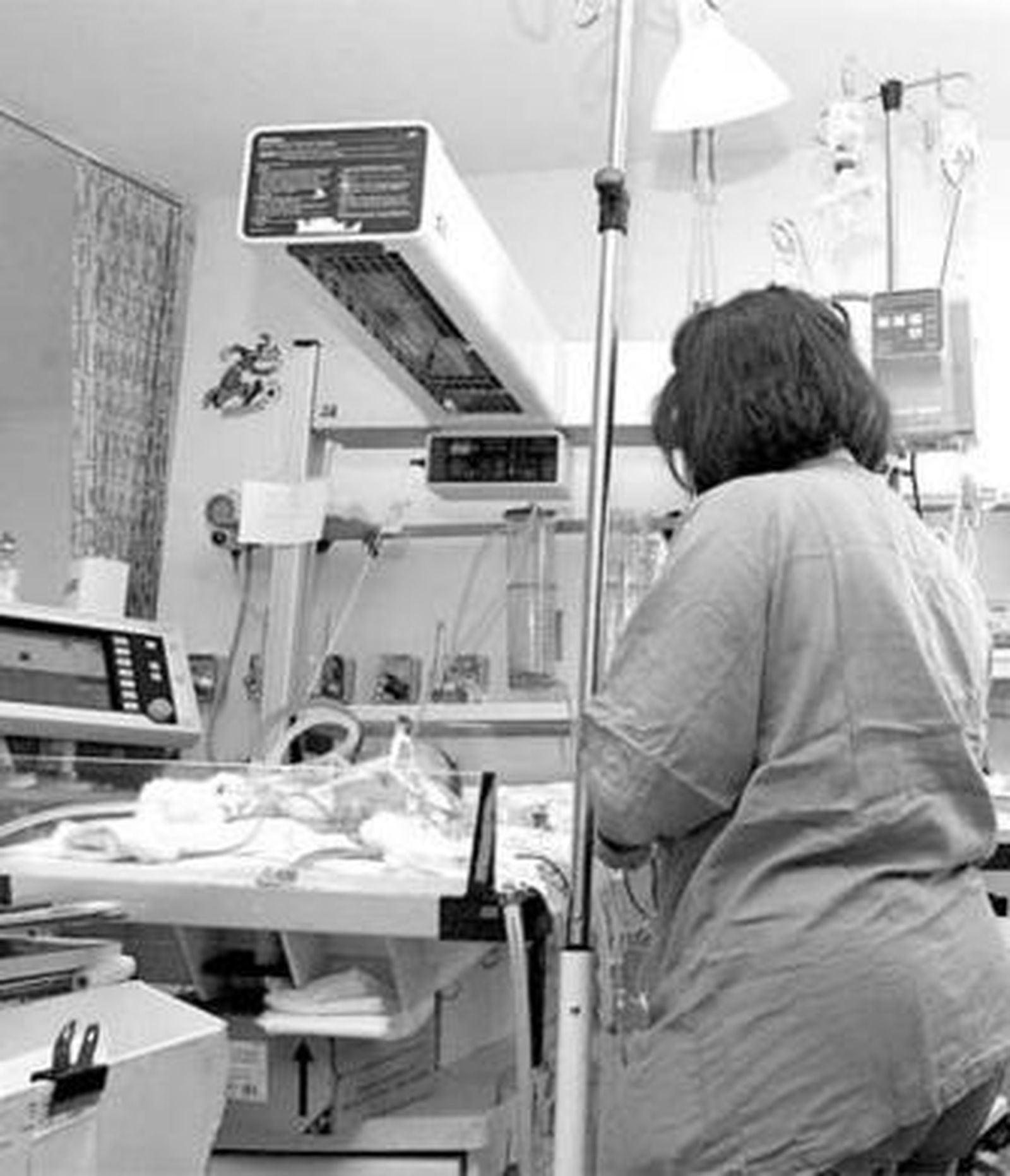 Una enfermera cuida a un bebé enfermo en el Reina Sofía.