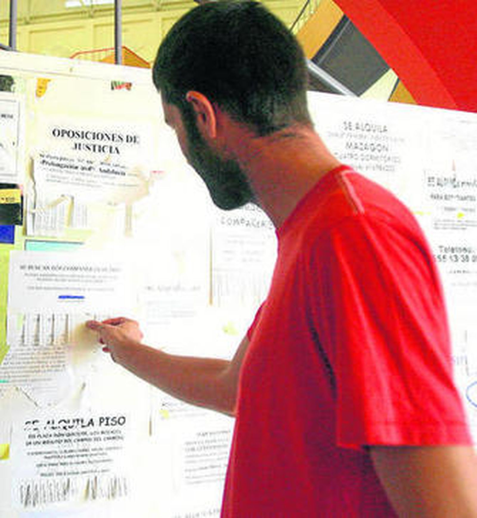 Un estudiante mira un tablón en la UHU en el que se ofertan alojamientos.