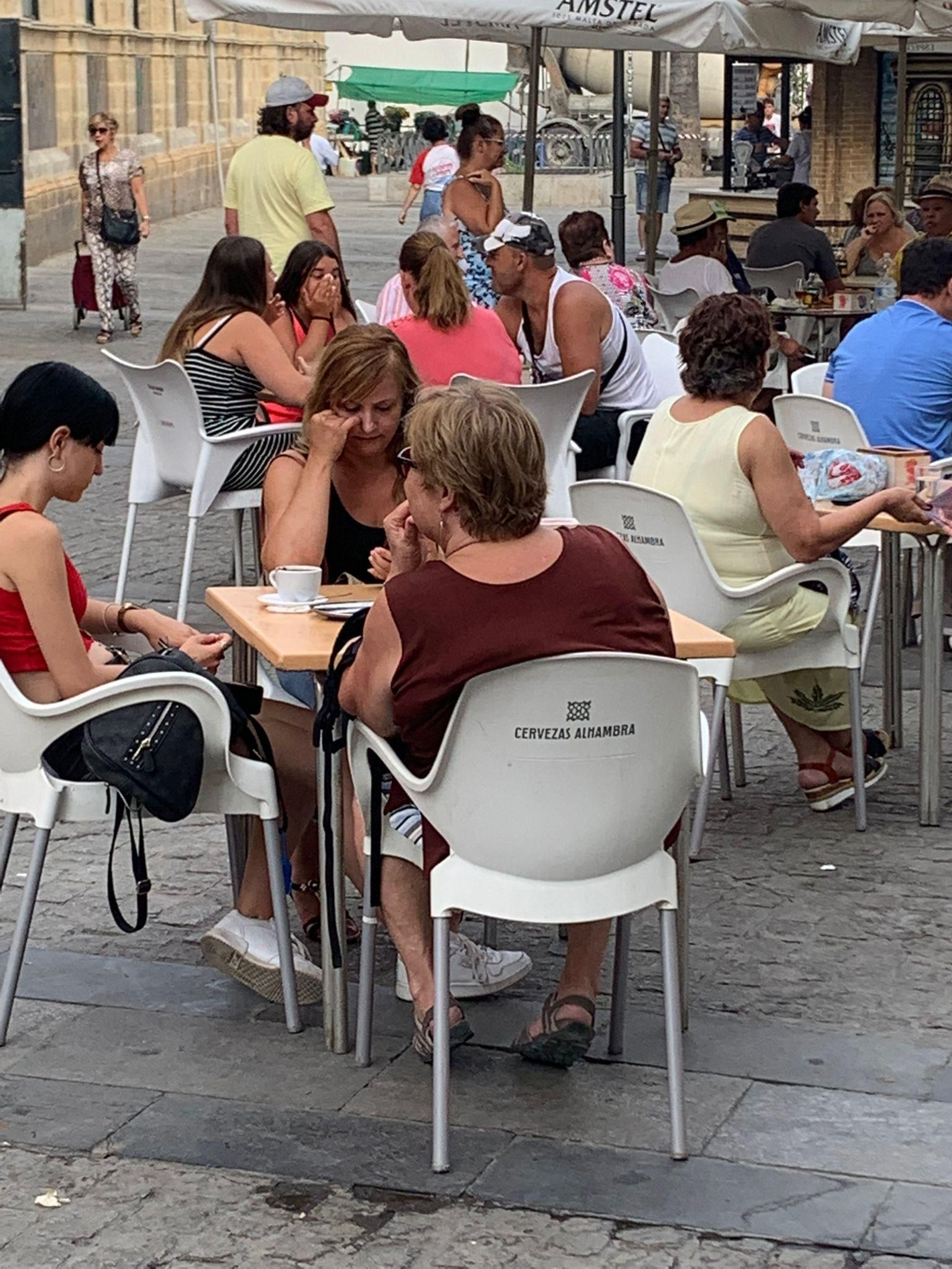 Una joven sentada en una terraza de Doña Blanca se tapa la nariz con las manos por el mal olor.