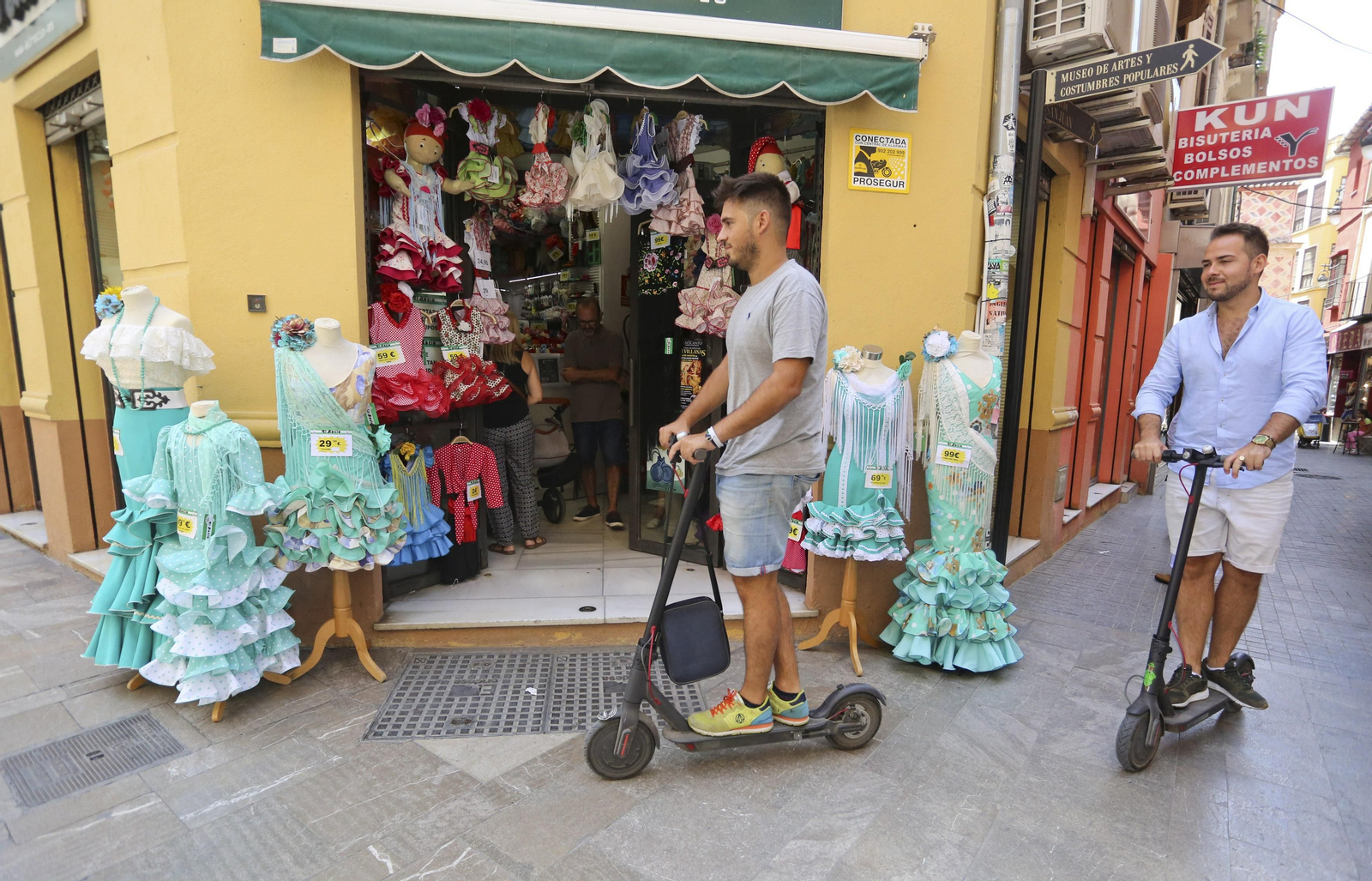 Dos personas, ayer, con el patinete por las calle del Centro de Málaga.