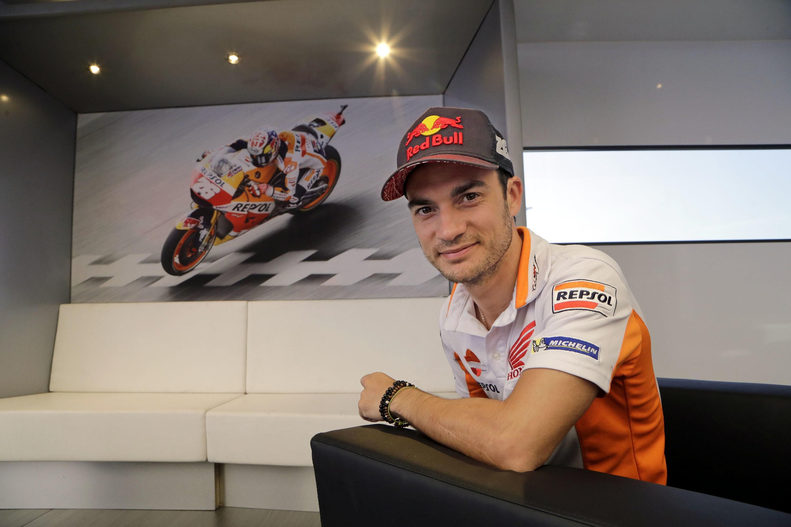 Dani Pedrosa posa junto a un cartel con una fotografía suya en acción.