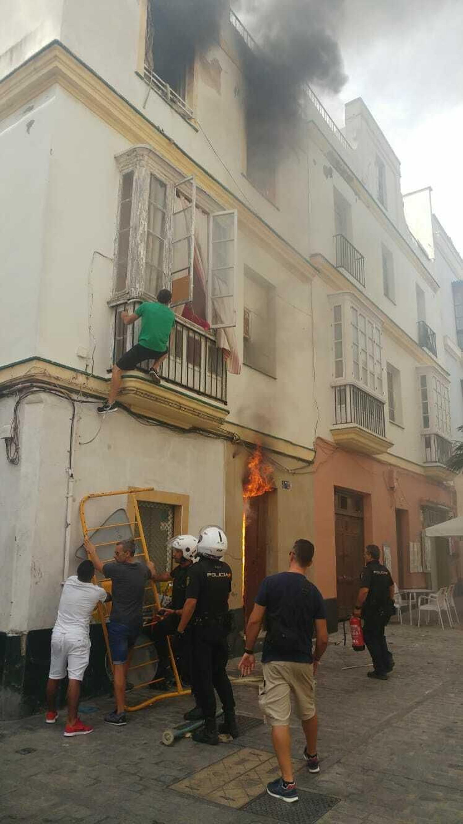 Un hombre escapa de las llamas ayudado por policía y vecinos.