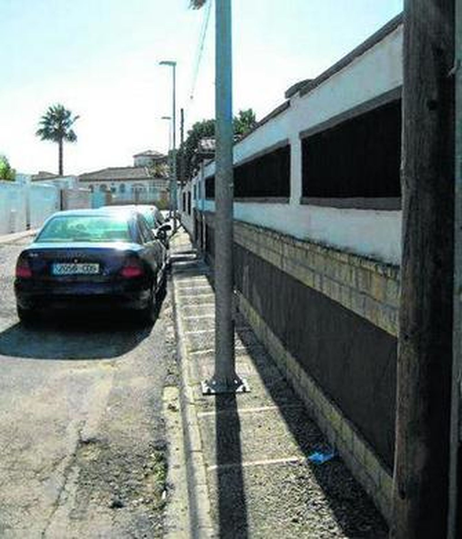 Farolas y postes de madera en una acera de una calle de Los Gallos.