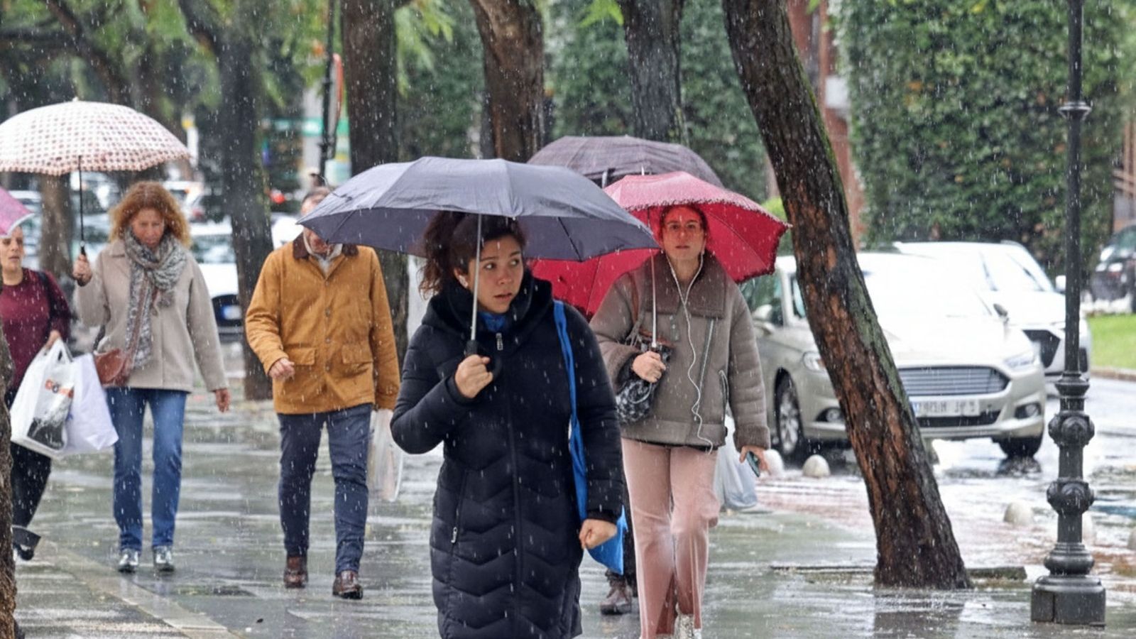 Varias personas con paraguas durante la lluvia en Huelva.