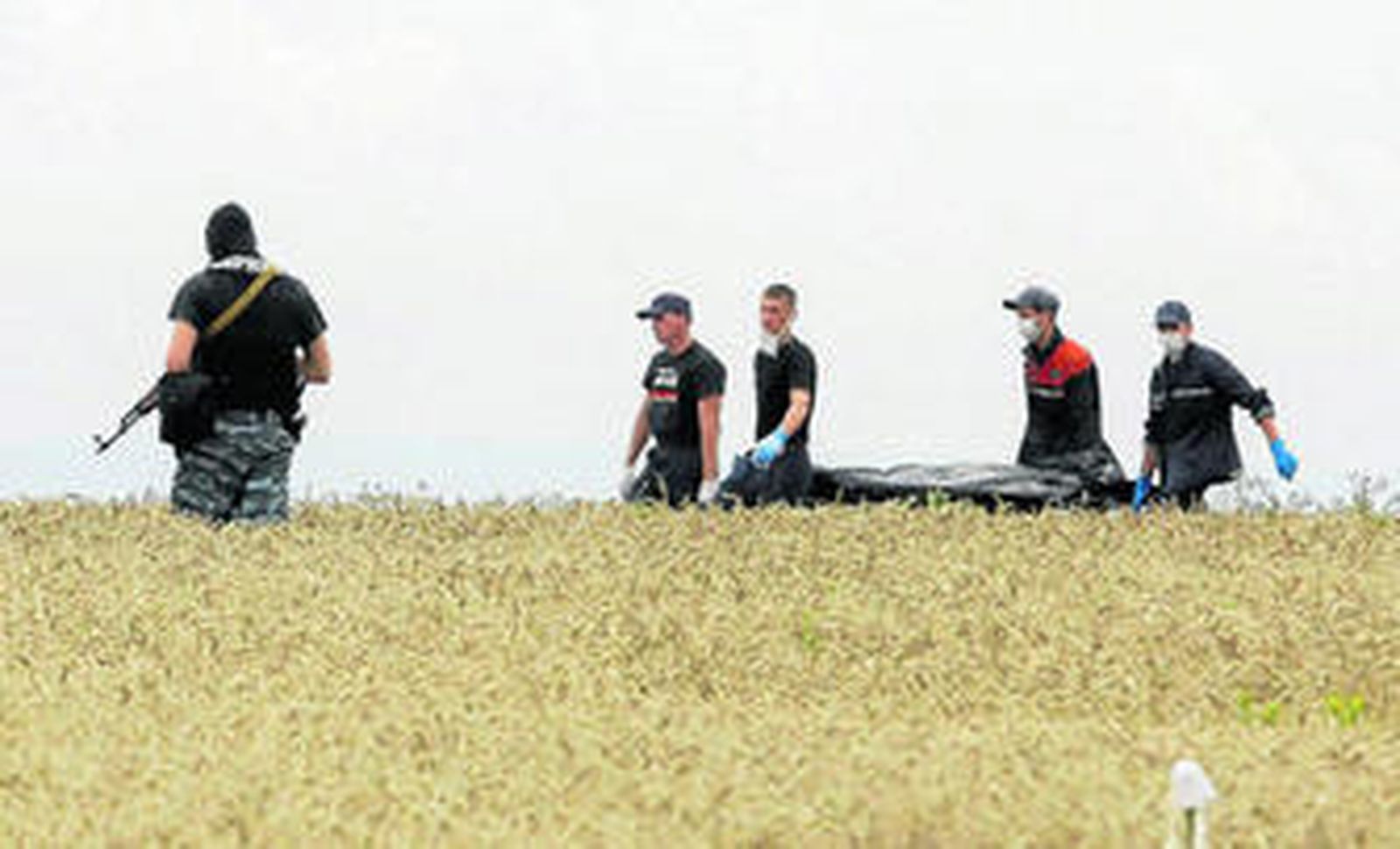 Miembros de los equipos de rescate portan cuerpos de los pasajeros del avión siniestrado en una camilla.