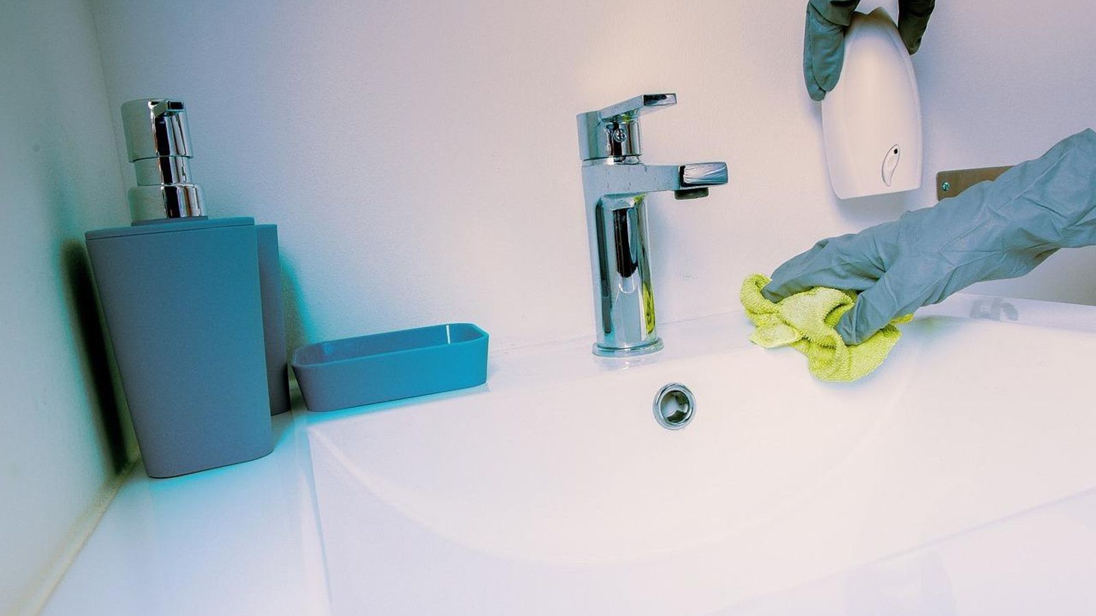 Una persona repasa el lavabo durante su labor de limpiar el baño