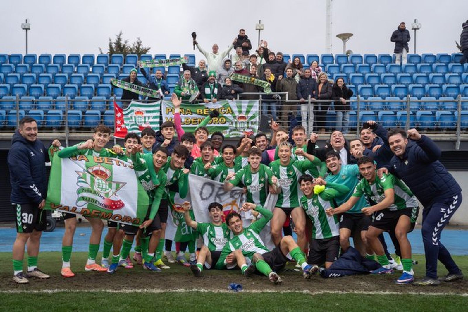 El Betis DH juvenil celebra el triunfo en Valdebebas con los béticos presentes en las gradas.