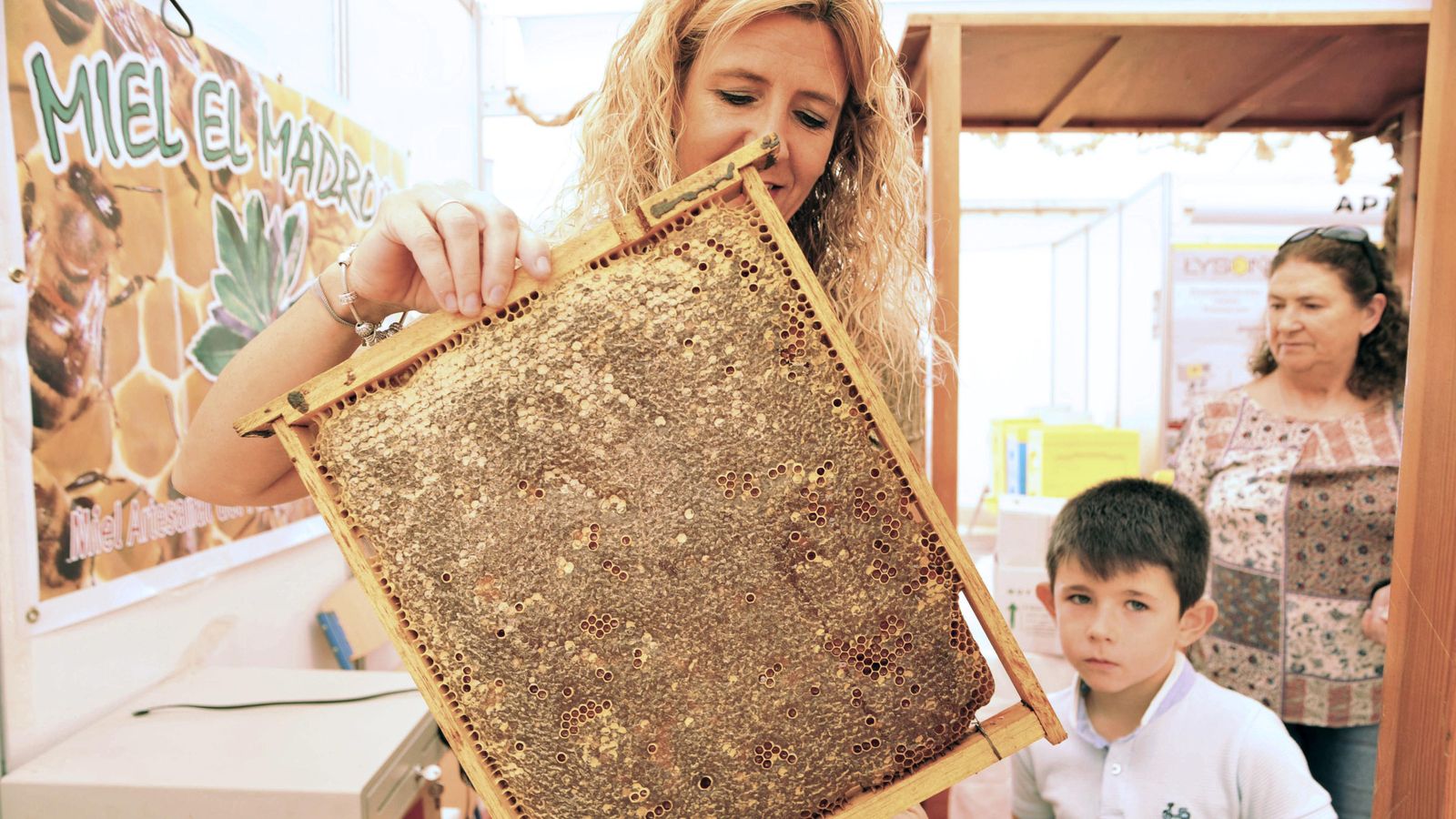 Una mujer con un cuadro de  cera y miel  en la  Feria de la Apicultura de 2018.