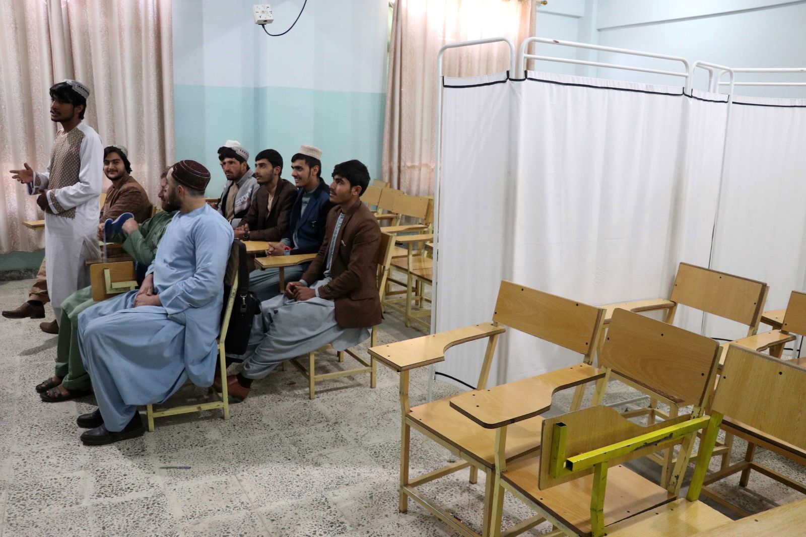 Estudiantes varones reciben clase junto a las sillas vacías destinadas a las alumnas en un instituto de Kandahar.