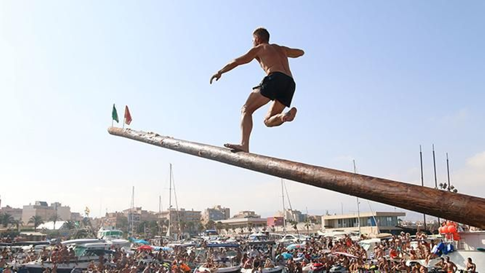 Un joven trepa por la cucaña