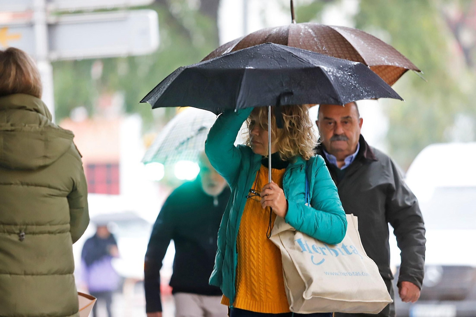 Dos personas se protegen de la lluvia con sus paraguas en Huelva.