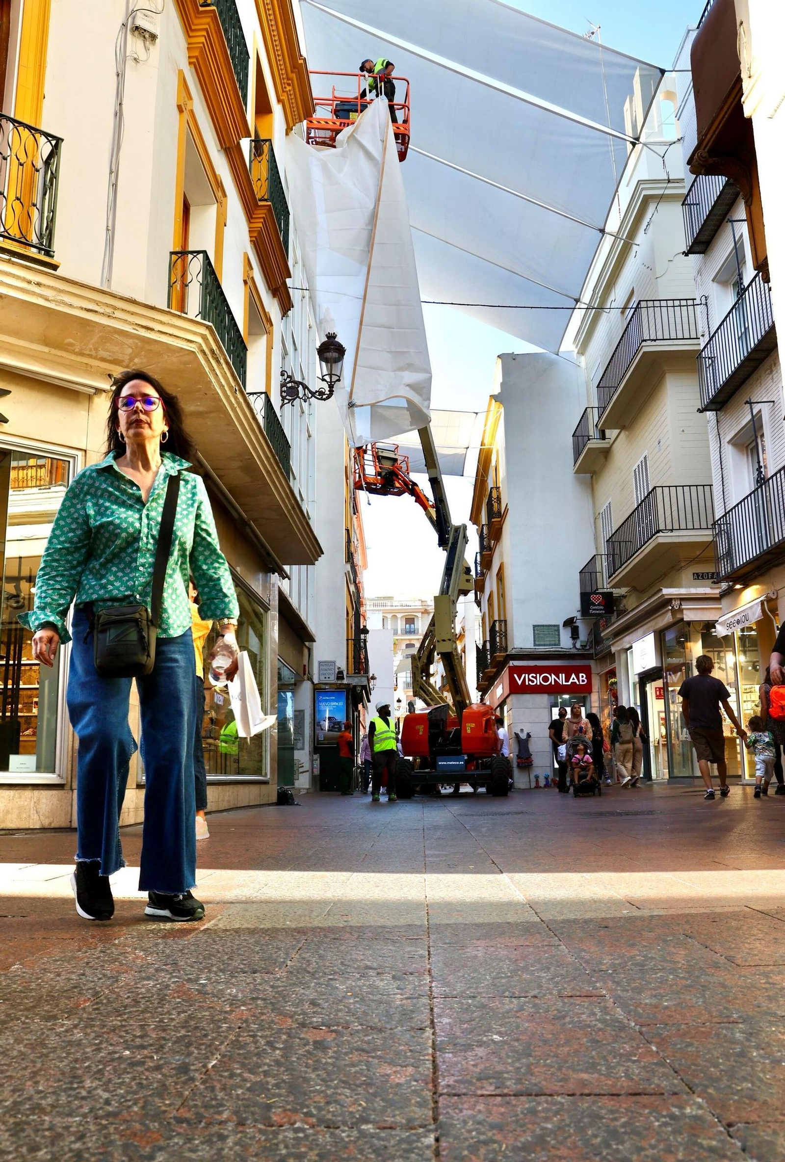Colocación de toldos en la calle Sierpes con la cera sin retirar