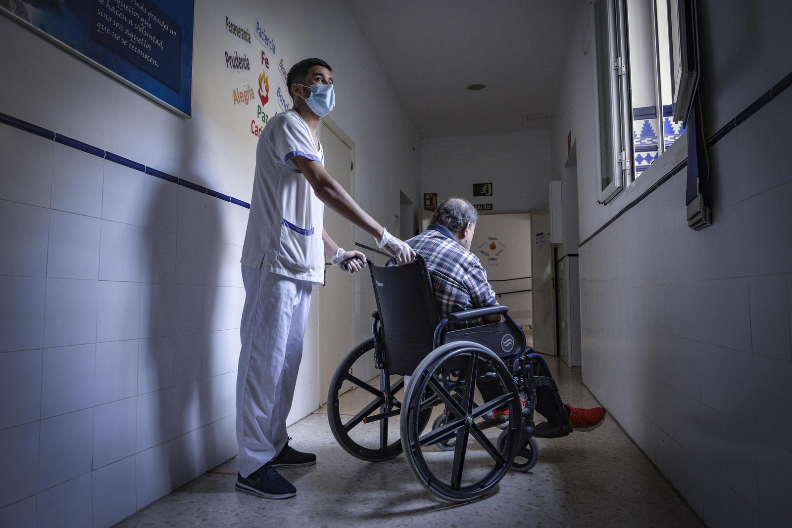 Un joven atiende a un hombre acogido en el Centro Miguel de Mañara de Sevilla.