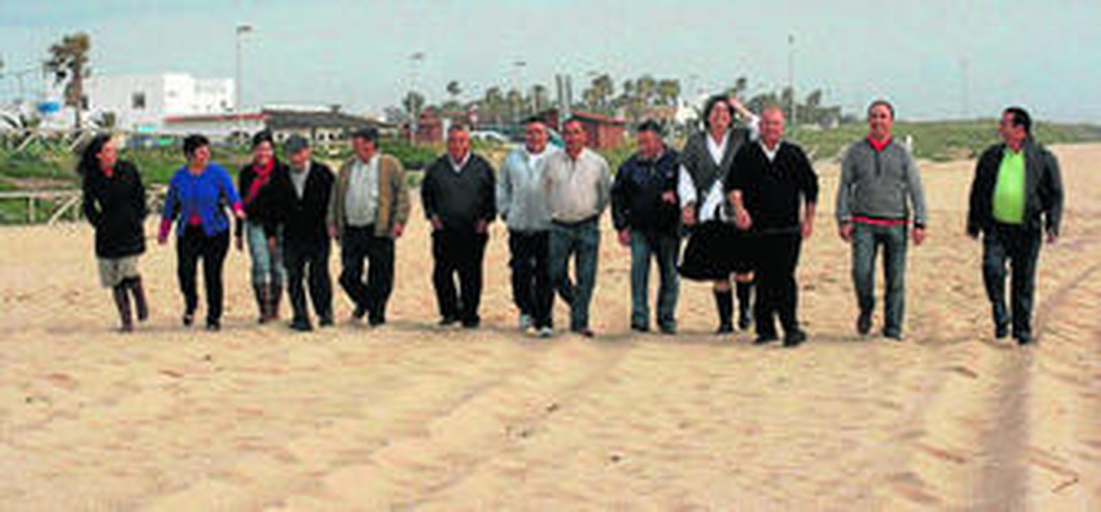 Representantes de asociaciones de vecinos, padres y madres de alumnos, comerciantes y mayores de El Palmar caminan por la playa.