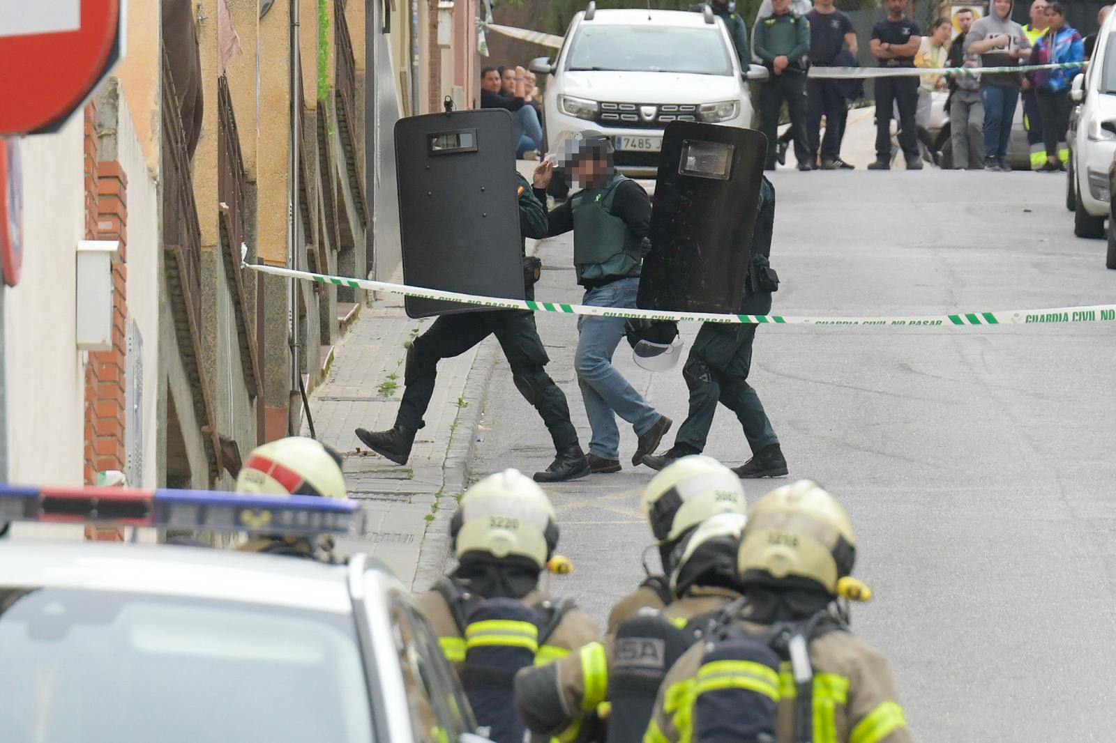 El mediador, escoltado, se dispone a entrar en la casa.