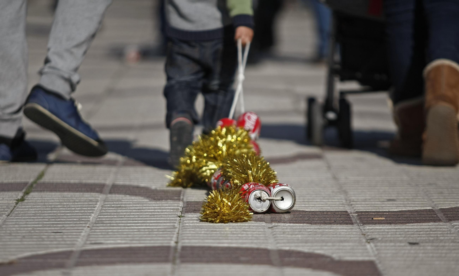 Un niño acarrea varias latas de refresco adornadas un día de Reyes.