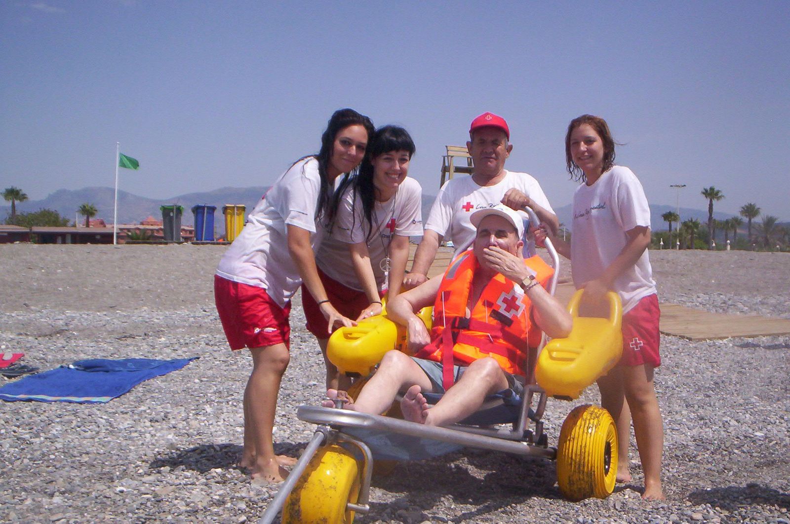 Voluntarios de la Cruz Roja los acompañan durante el baño en la silla anfibia