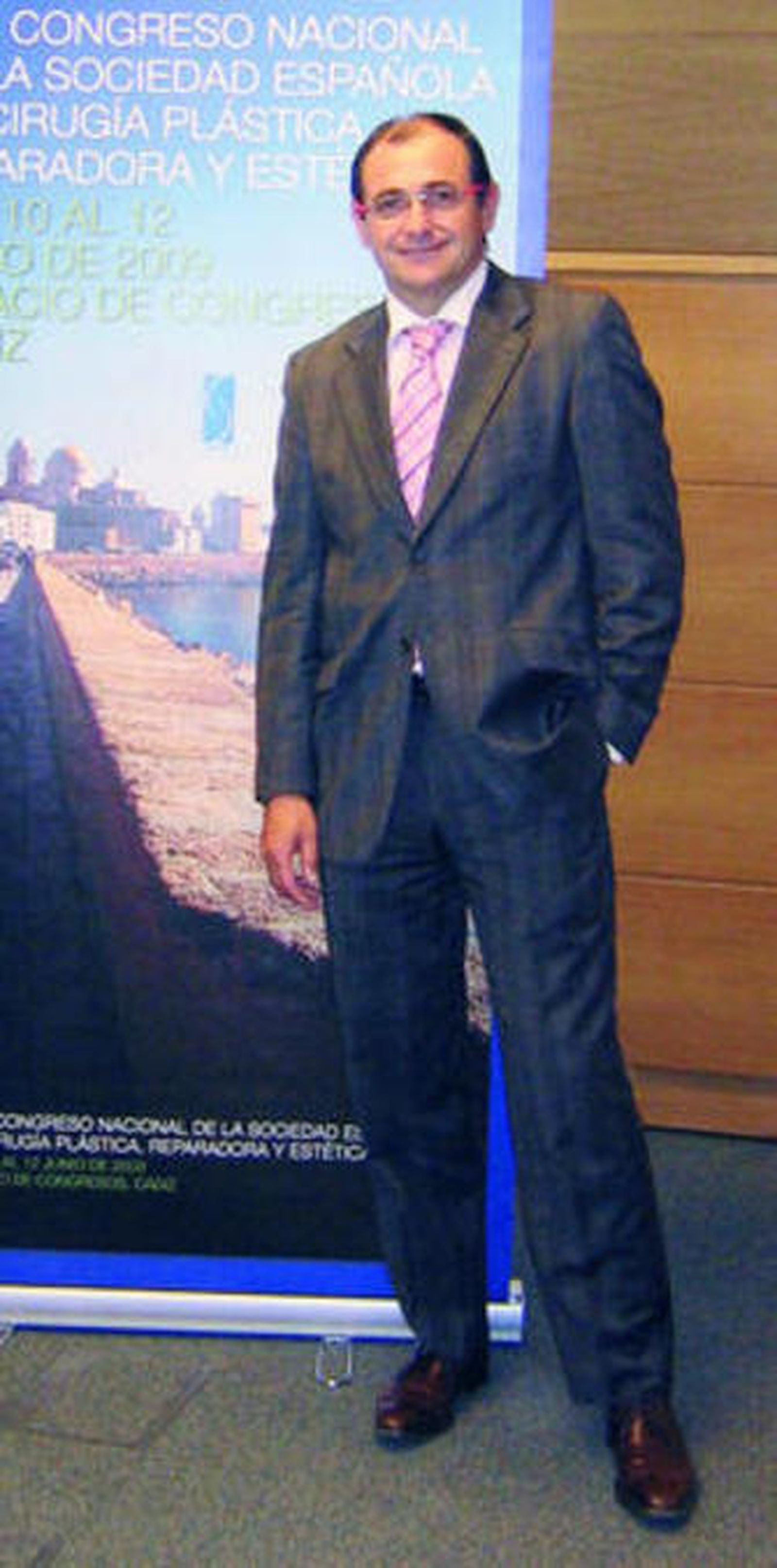 Maestro junto al cartel que anuncia el congreso anual.