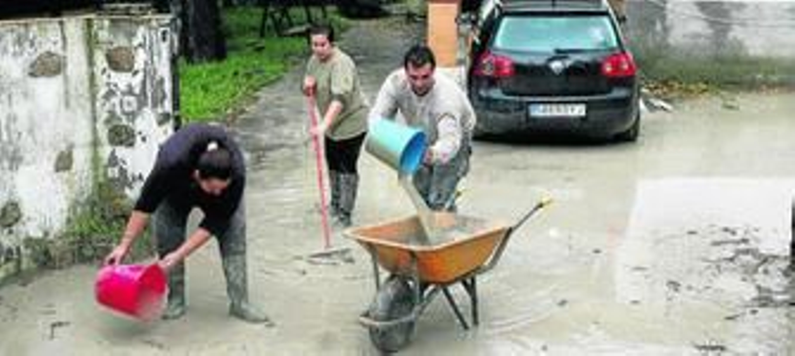 Una familia extrae el agua y el lodo de su parcela.