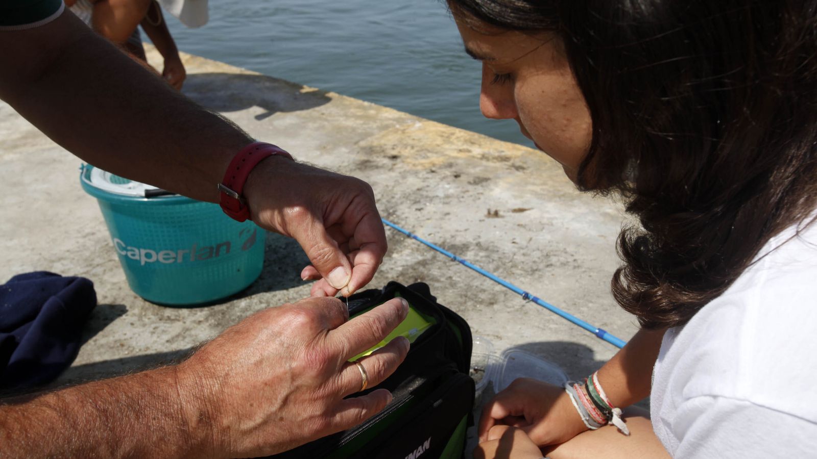 Uno de los monitores enseña a una alumna a 'empatar' un anzuelo