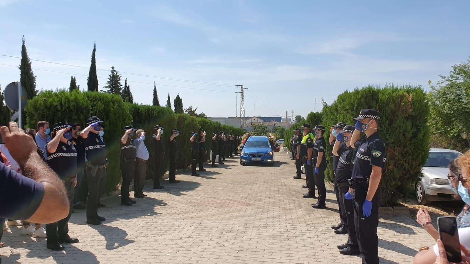 Policías locales saludan al paso del coche fúnebre.