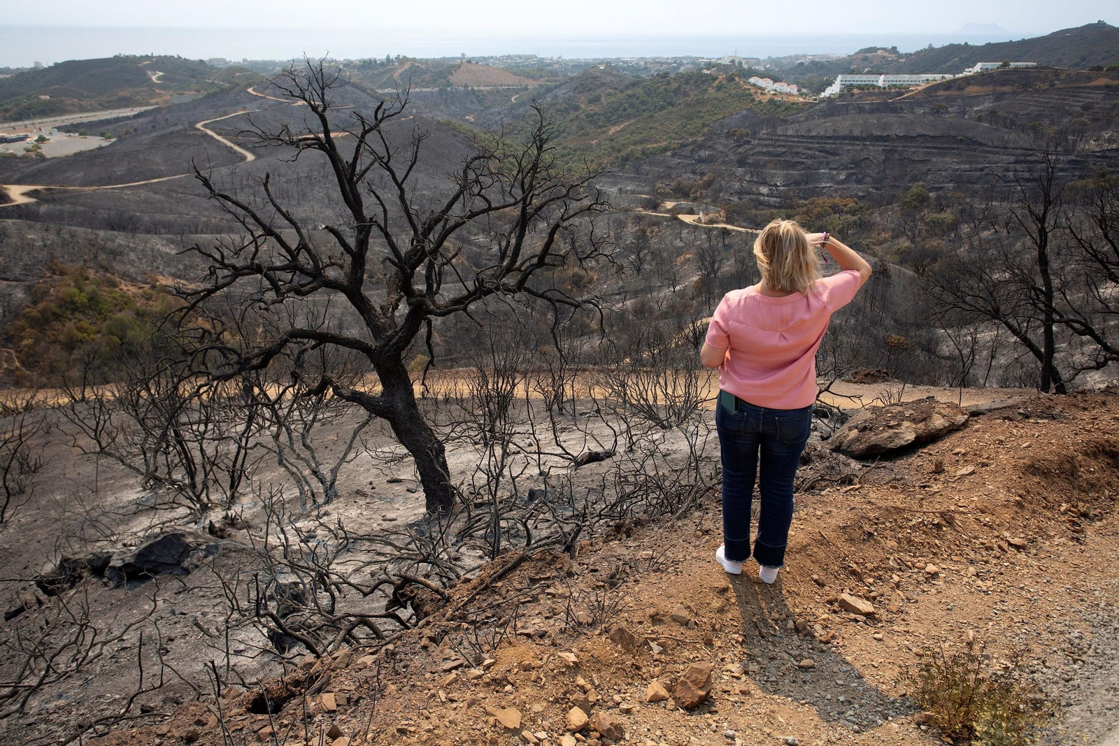 Una vecina de Estepona contempla la superficie calcinada en el incendio de Sierra Bermeja en 2022