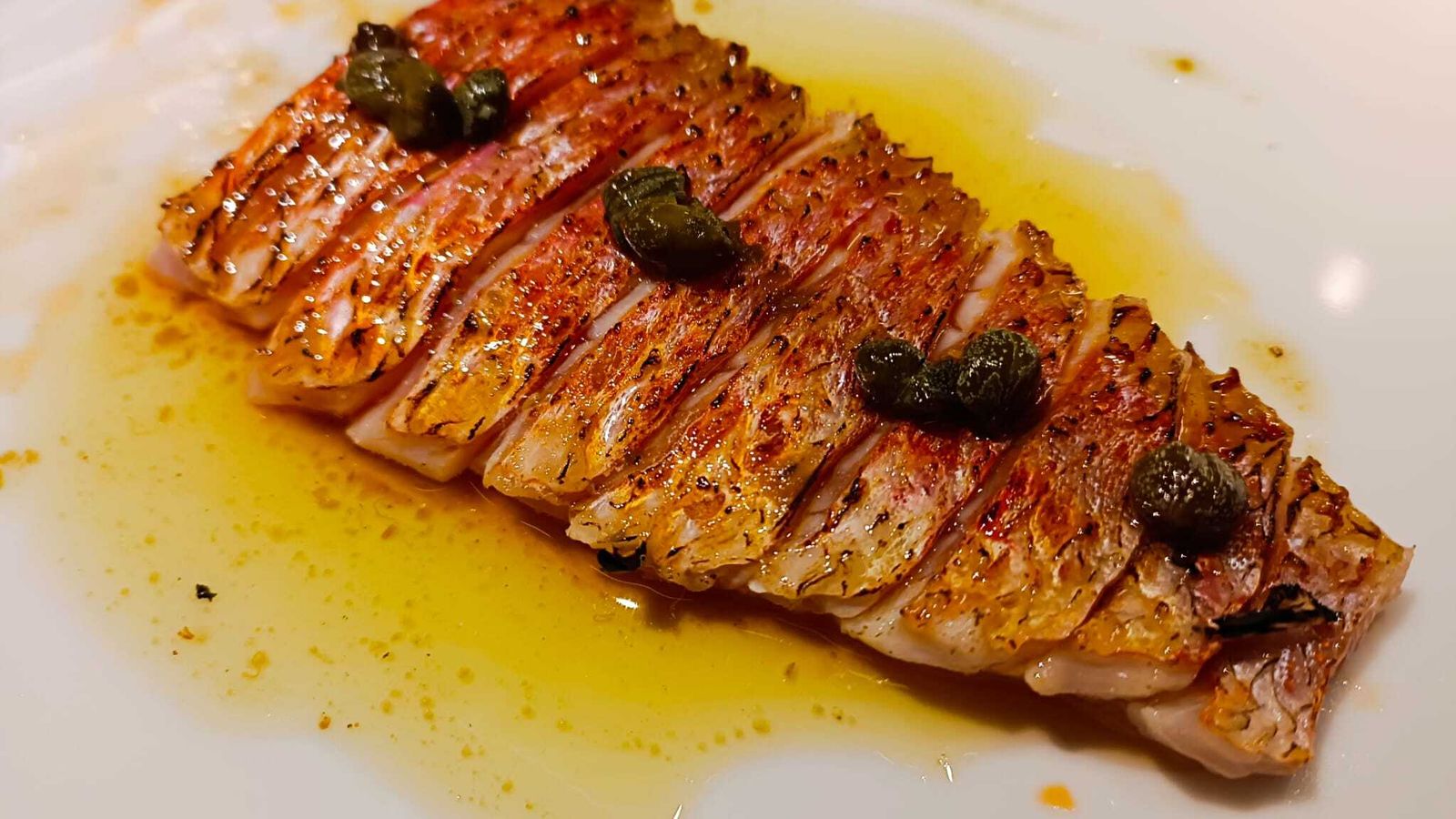 El salmonete, ligeramente pasado por el soplete y con una salsa menier y alcaparras.