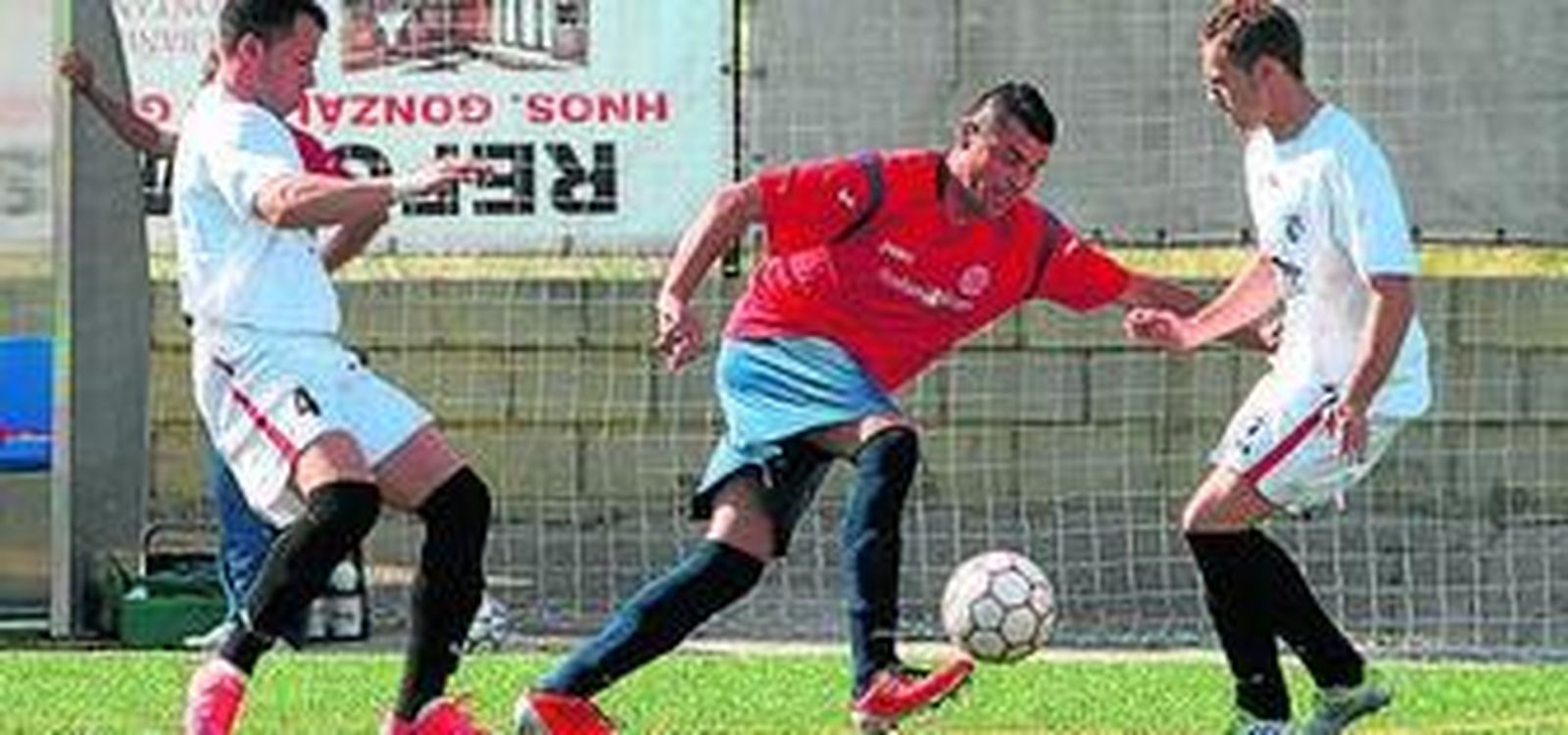 Un jugador de El Higuerón escapa de la presión de dos rivales.