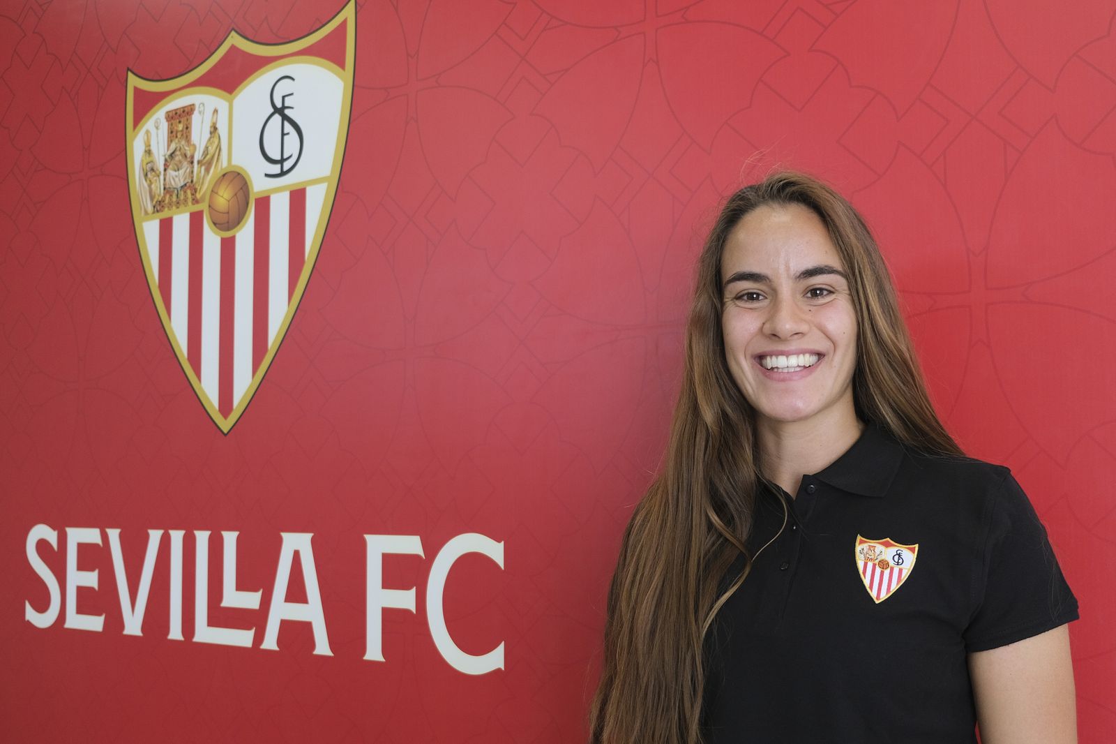 Diana Gomes posa con el polo del Sevilla delante del escudo del club.