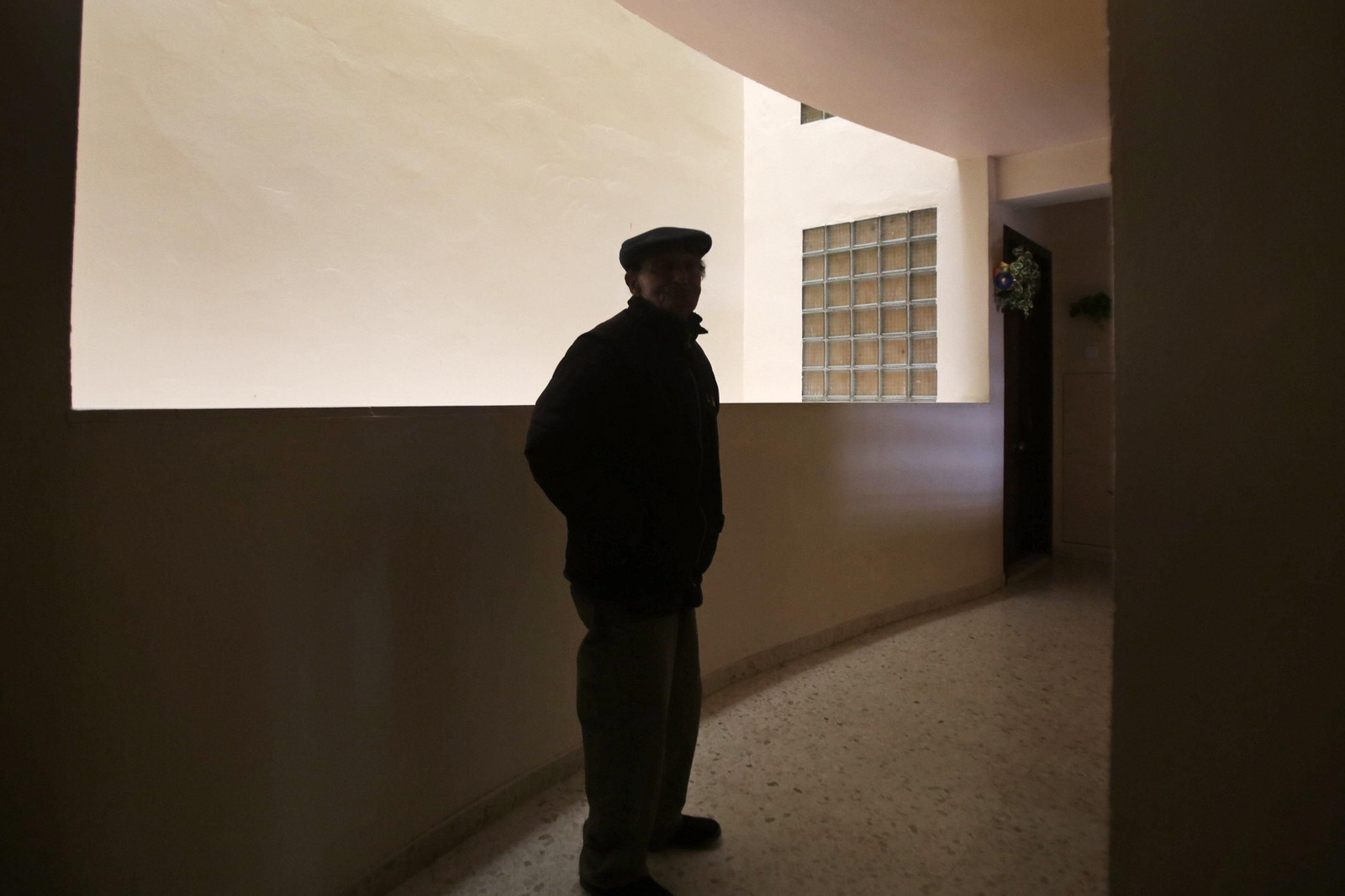 Una persona mayor en la entrada a su vivienda.