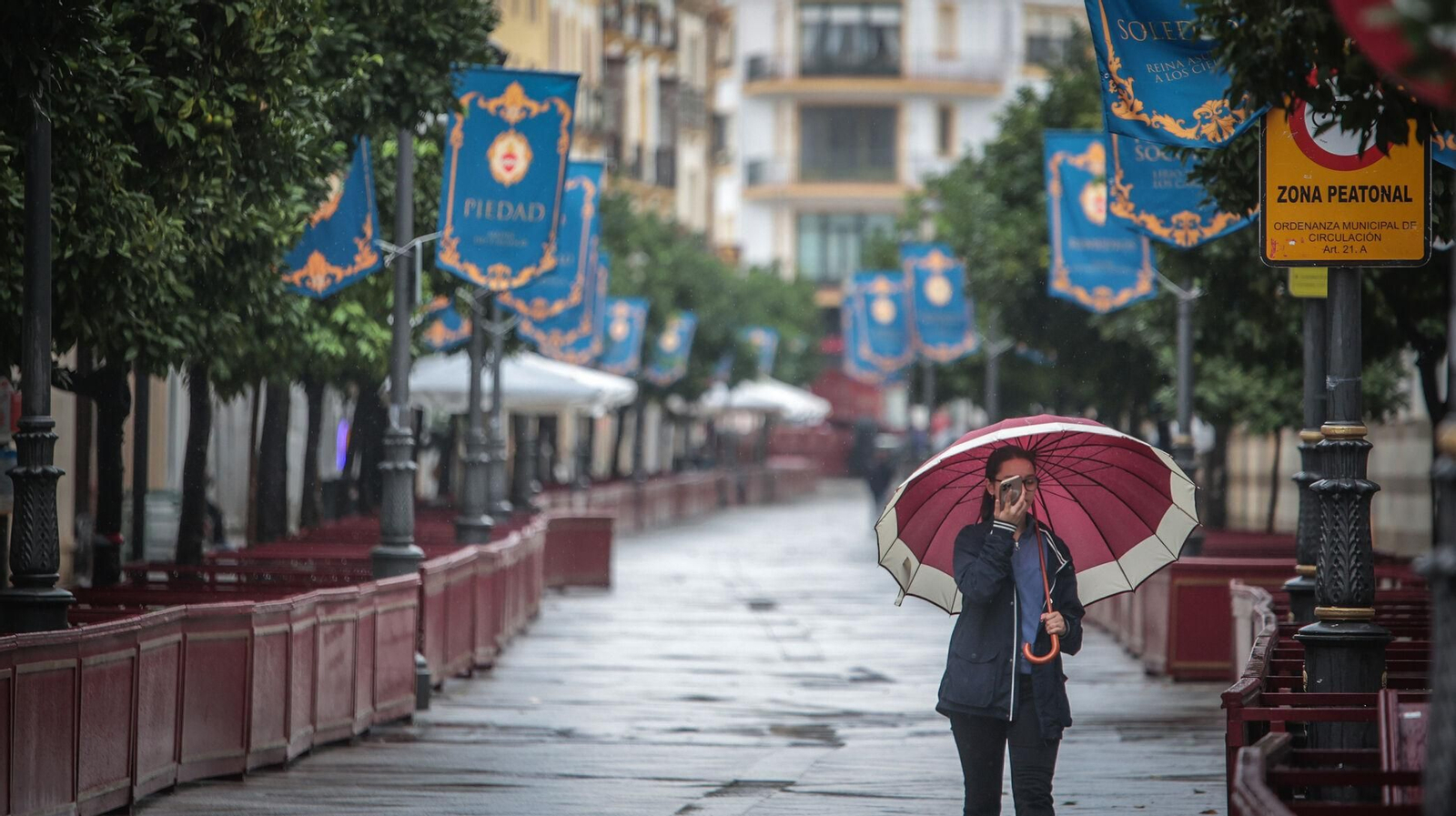 Una joven, paseando por la calle Larga con el paragüas en mano.
