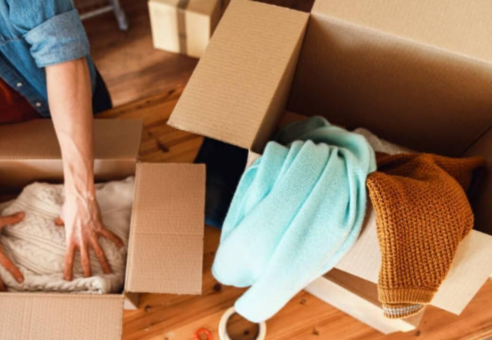 Una persona embala cajas con diferentes prendas de ropa a las que darle un segundo uso