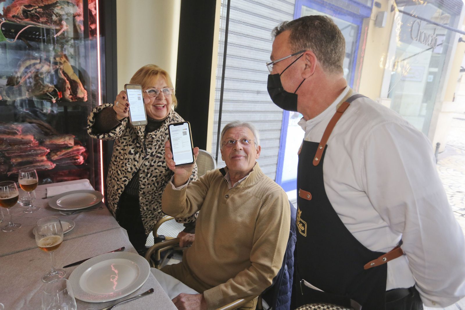 Dos clientes muestran el pasaporte Covid a un camarero