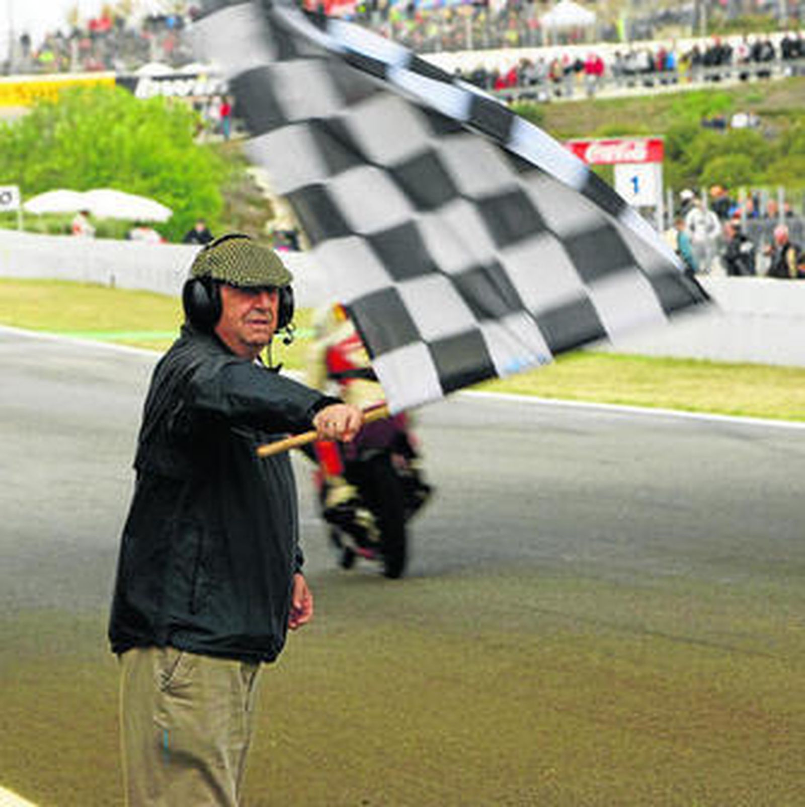 Alfredo Franco agita la bandera a cuadros al paso de un piloto de Moto3 bajo el 'ovni'.