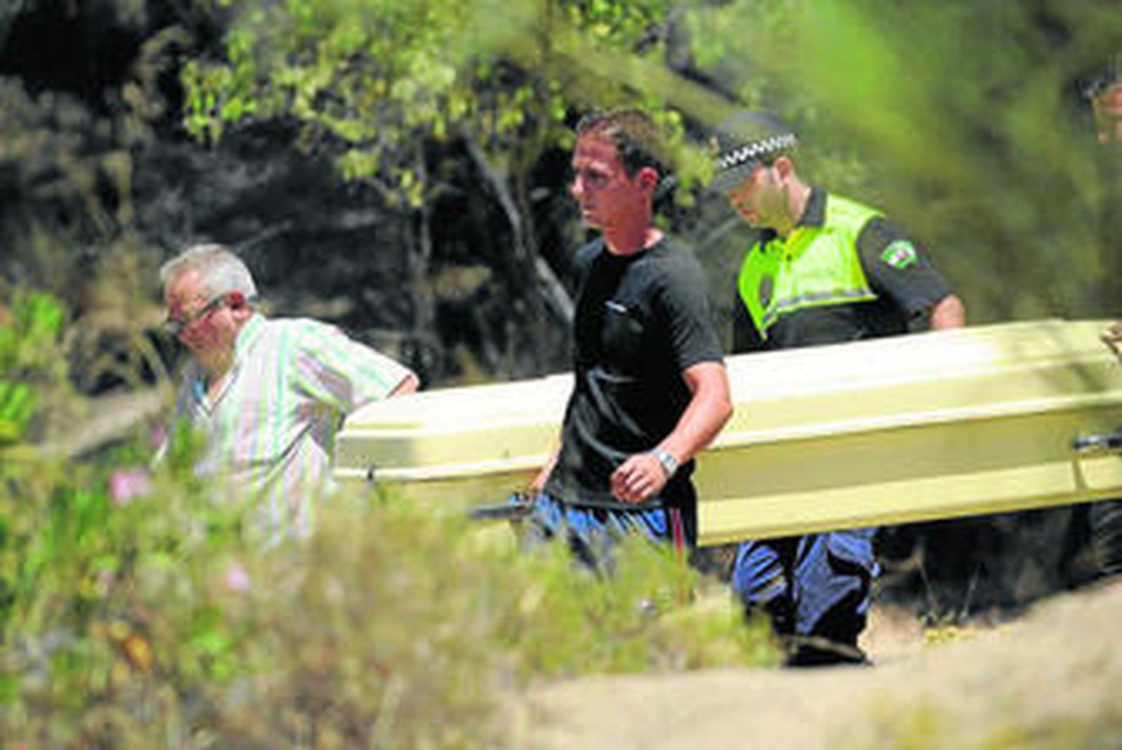 Un policía local y dos operarios, durante el traslado del féretro a través de la Sierra del Castillo.