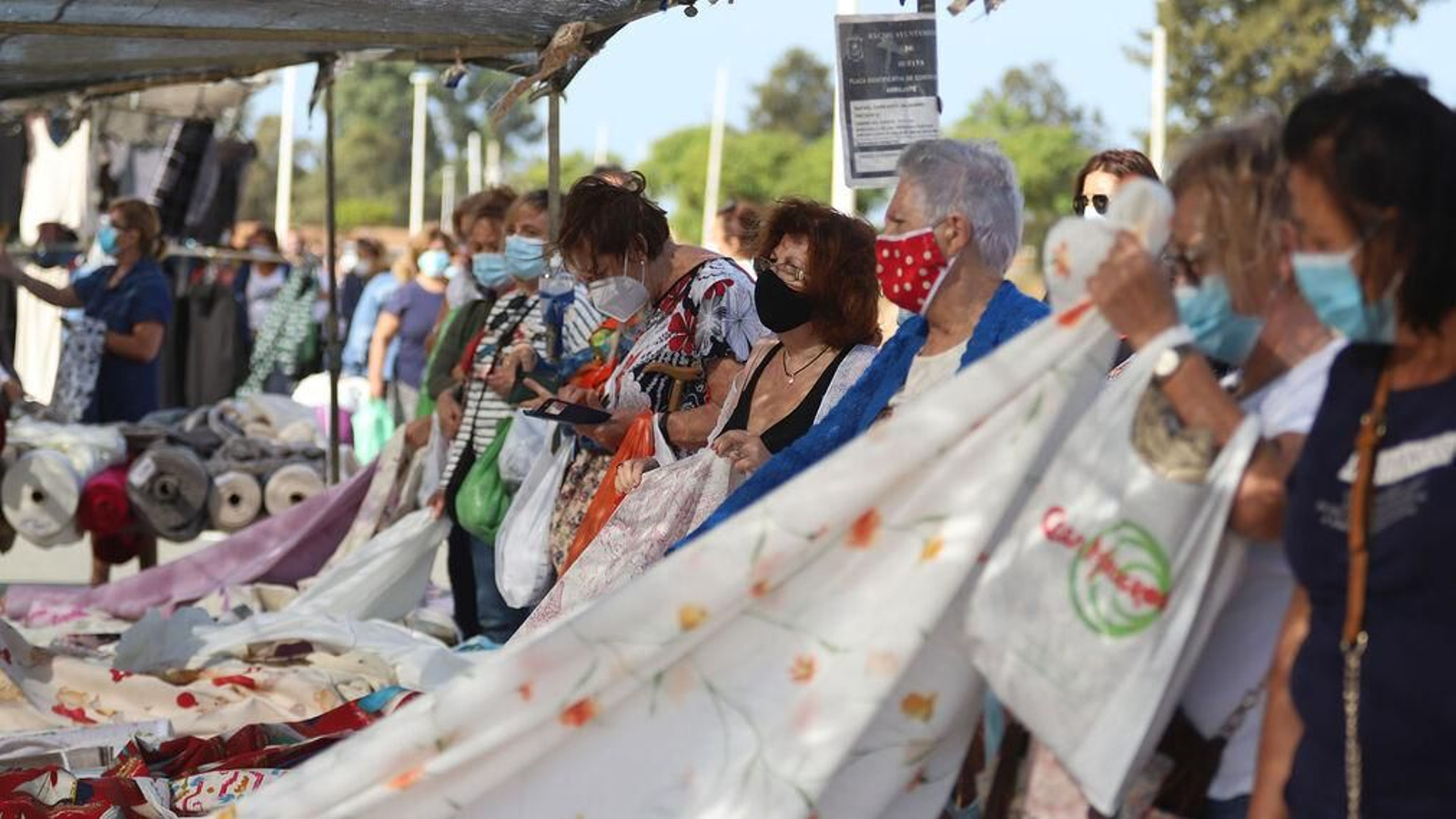 Varias mujeres en un puesto de tejidos al corte.