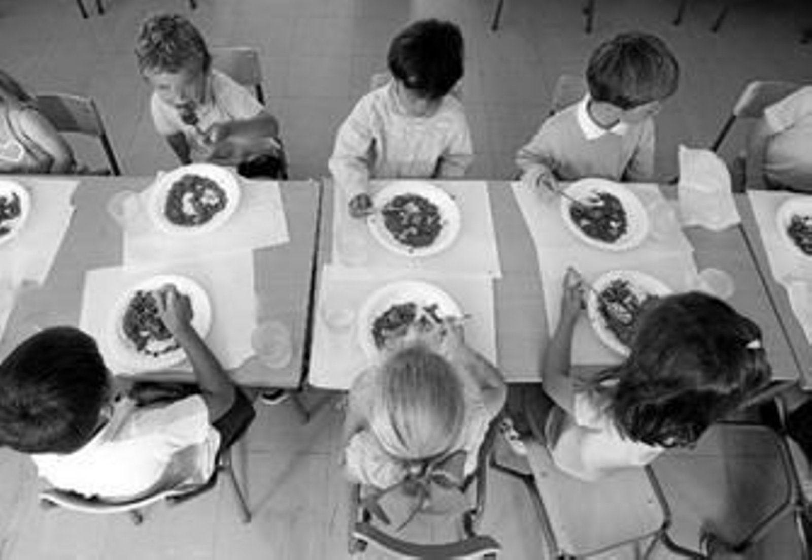 Unos niños comen un plato de legumbres en un comedor escolar.