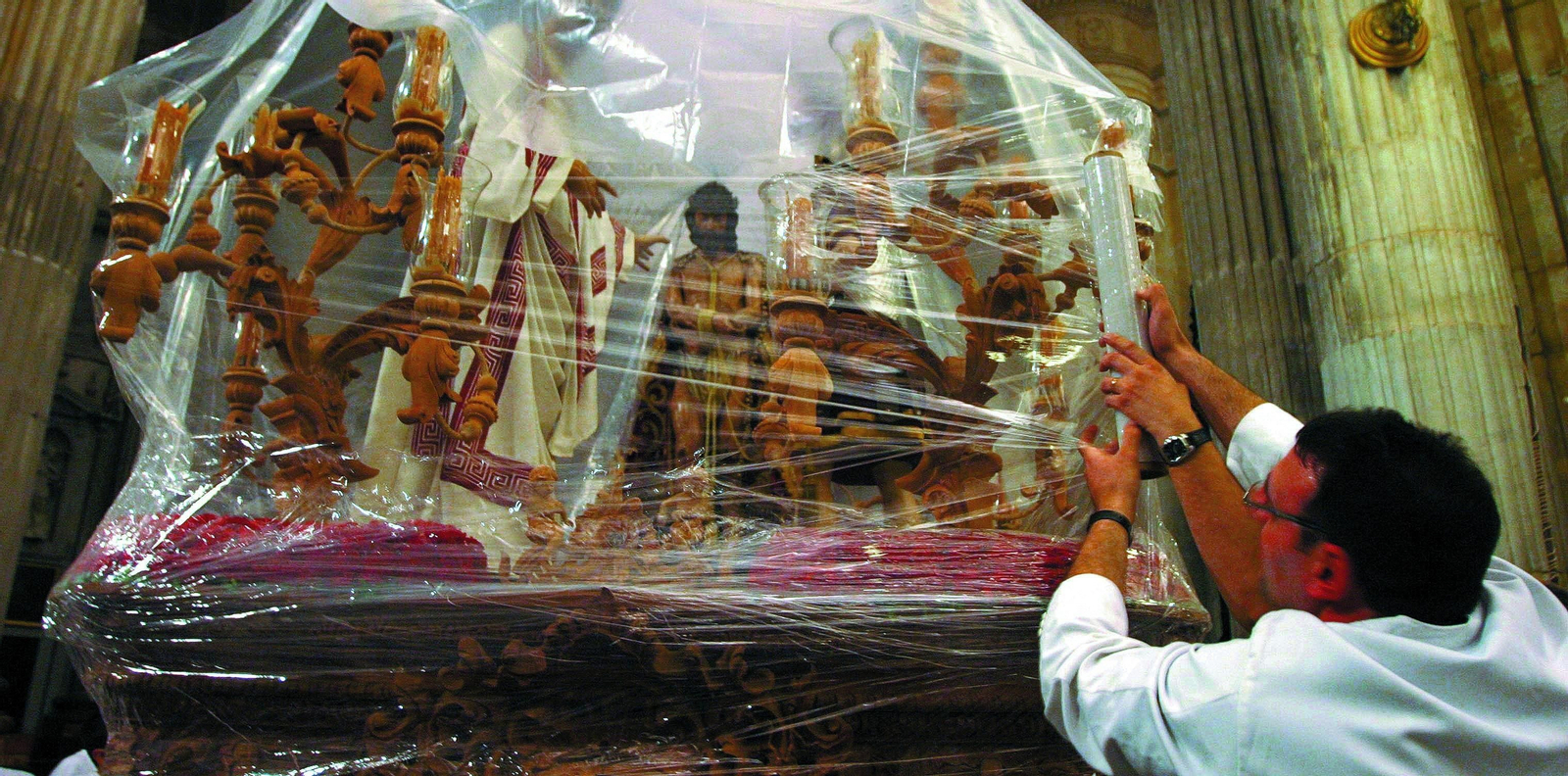 Un hermano de Ecce-Homo envuelve con un plástico el paso de misterio en 2005.