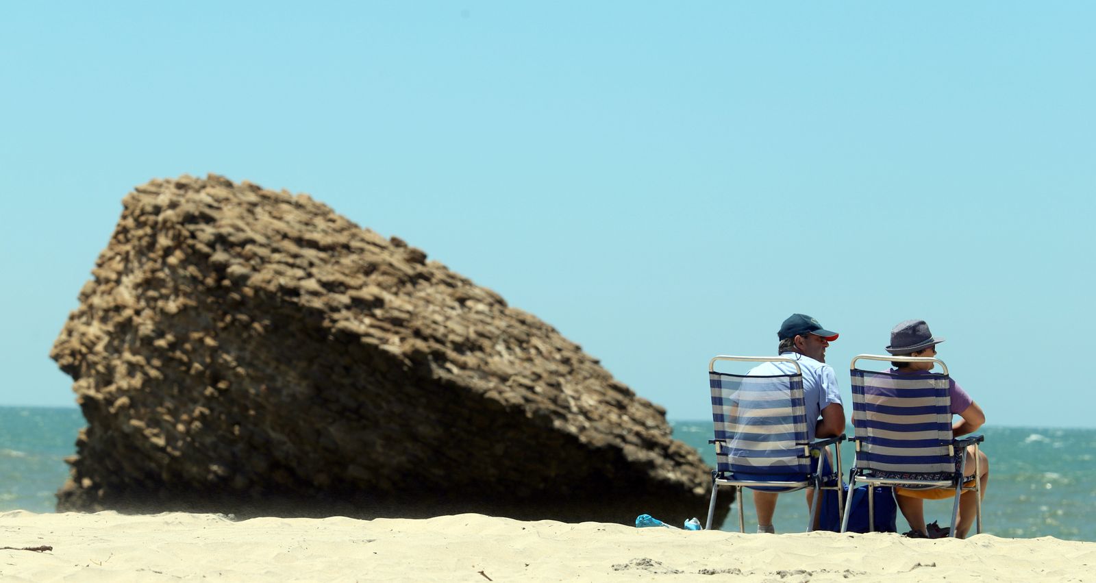 Dos personas sentadas en la playa de Matalascañas, ayer por la mañana.