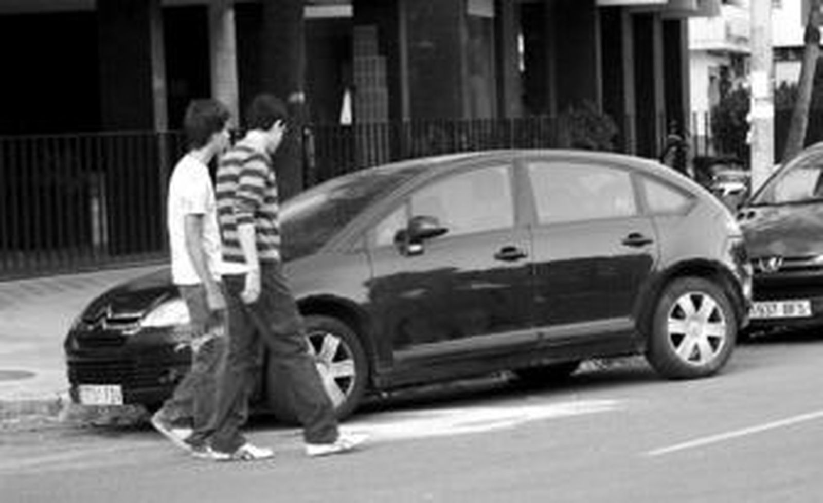 Dos jóvenes contemplan el serrín esparcido en la calzada para absorber las manchas de sangre.