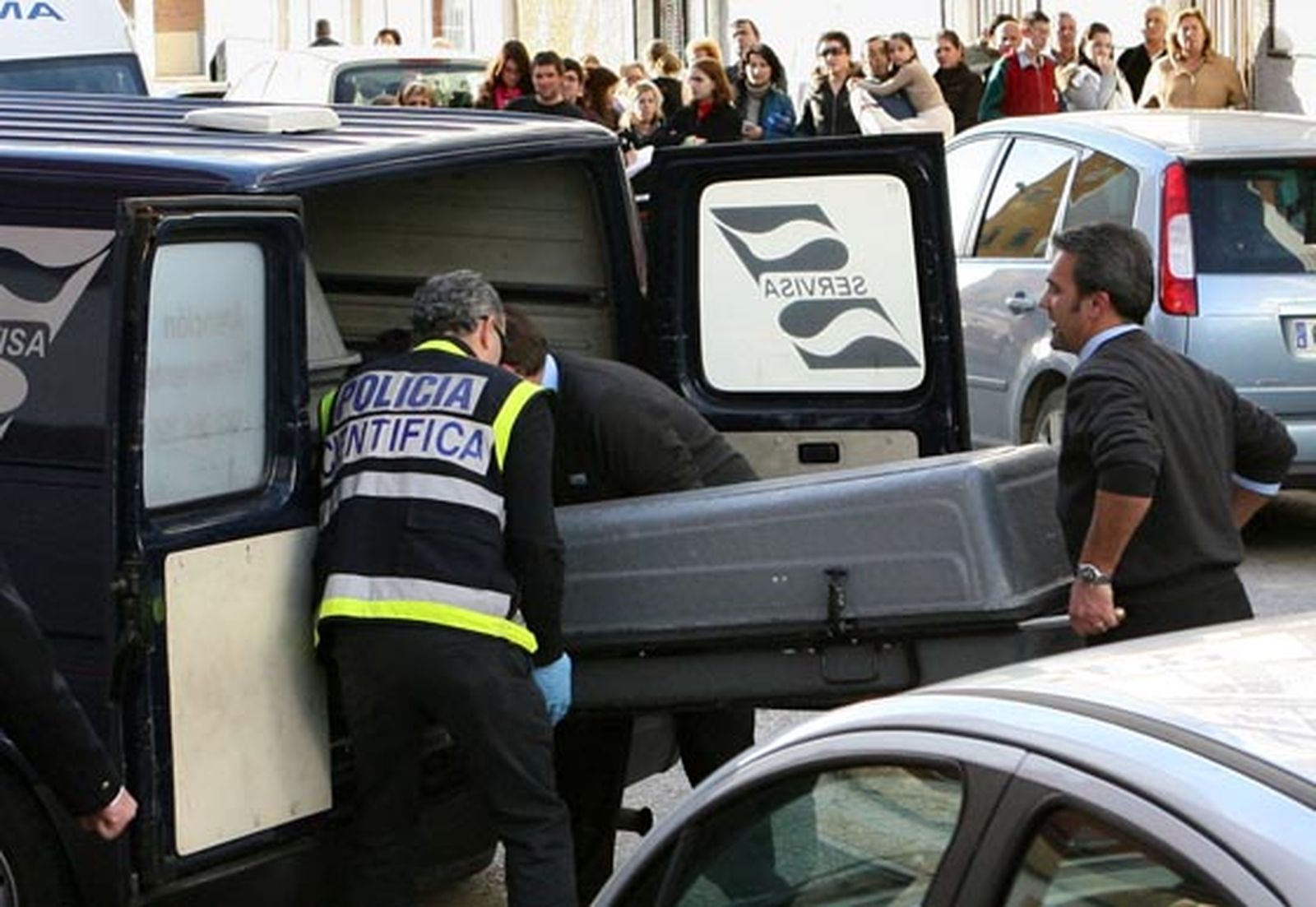 La multitud contempla el momento en el que el cadáver de la mujer asesinada era introducido en la furgoneta para ser trasladado.  Foto: Juan Carlos Mu?